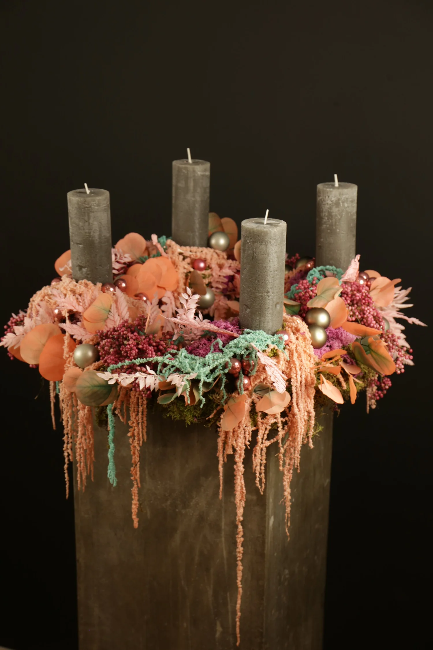 Corona preservada con cuatro velas y flores en tonos rosa y coral