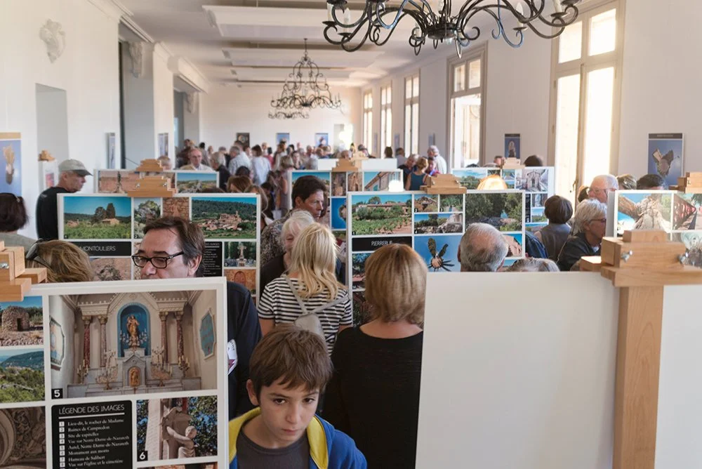 Public découvrant une exposition patrimoniale composée de panneaux photographiques en salle