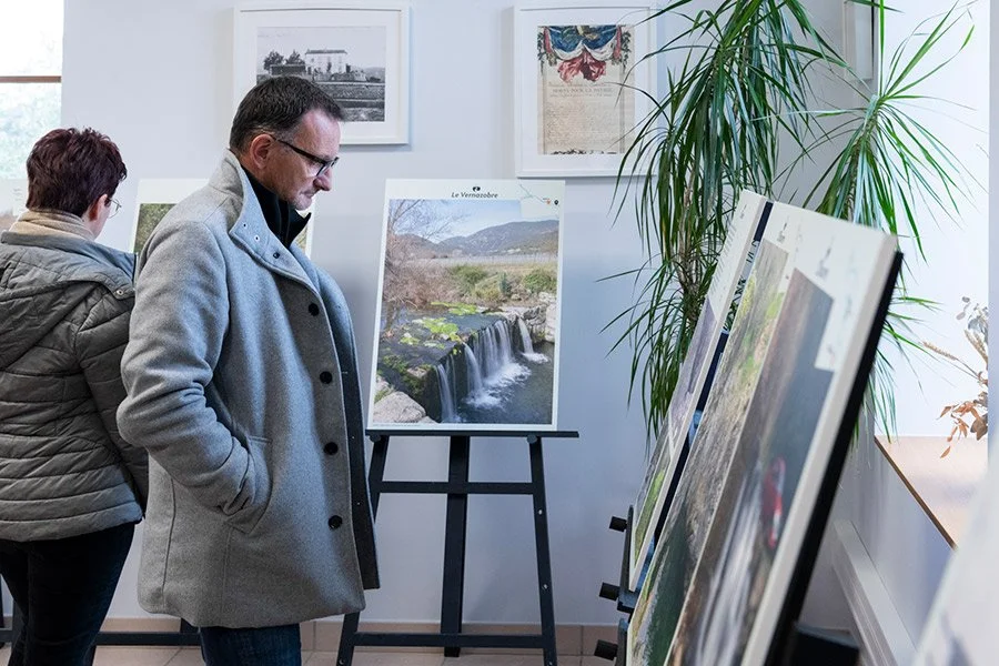 Visiteur observant des photographies lors d’une exposition patrimoniale en intérieur