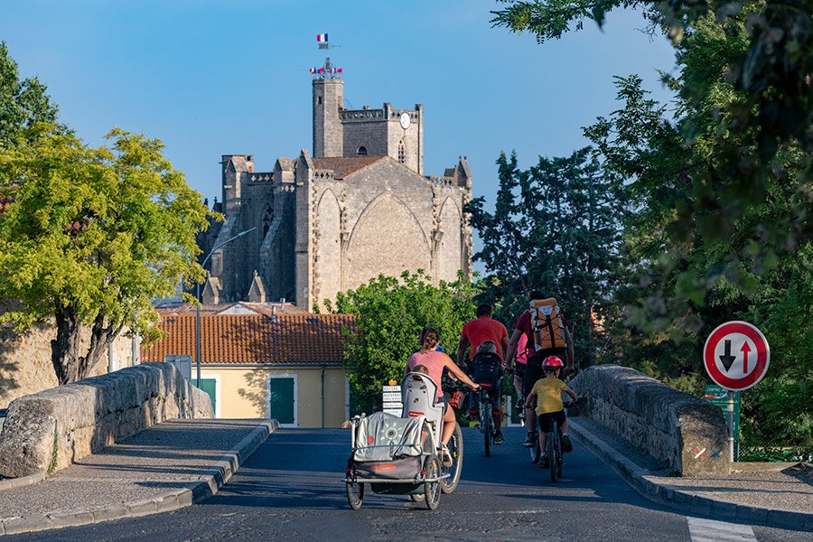 Reportage photographie éditoriale, une famille de touristes à vélo traversant un pont sur le canal du midi.