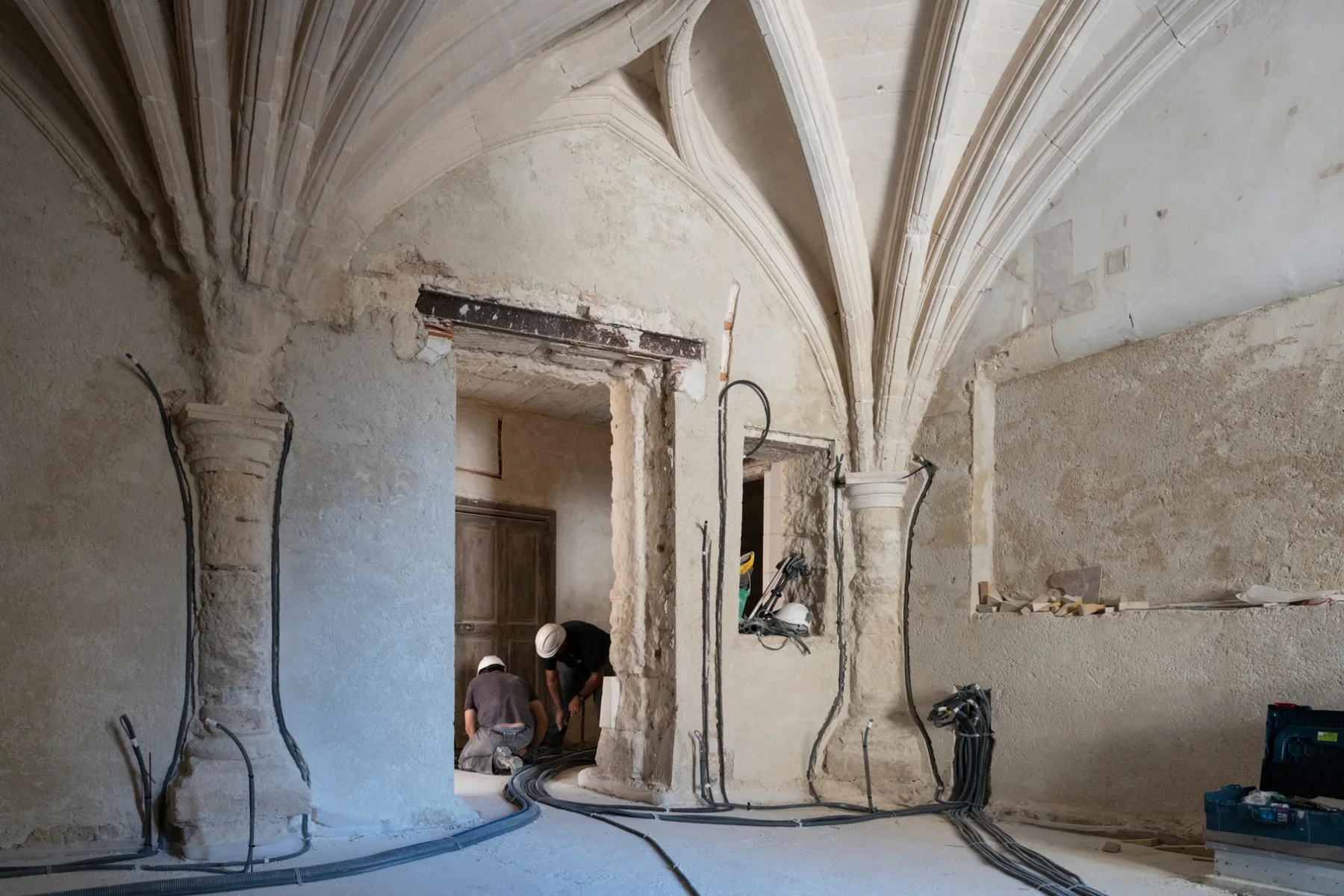 Artisans au travail dans un intérieur voûté lors de la restauration d’un bâtiment patrimonial