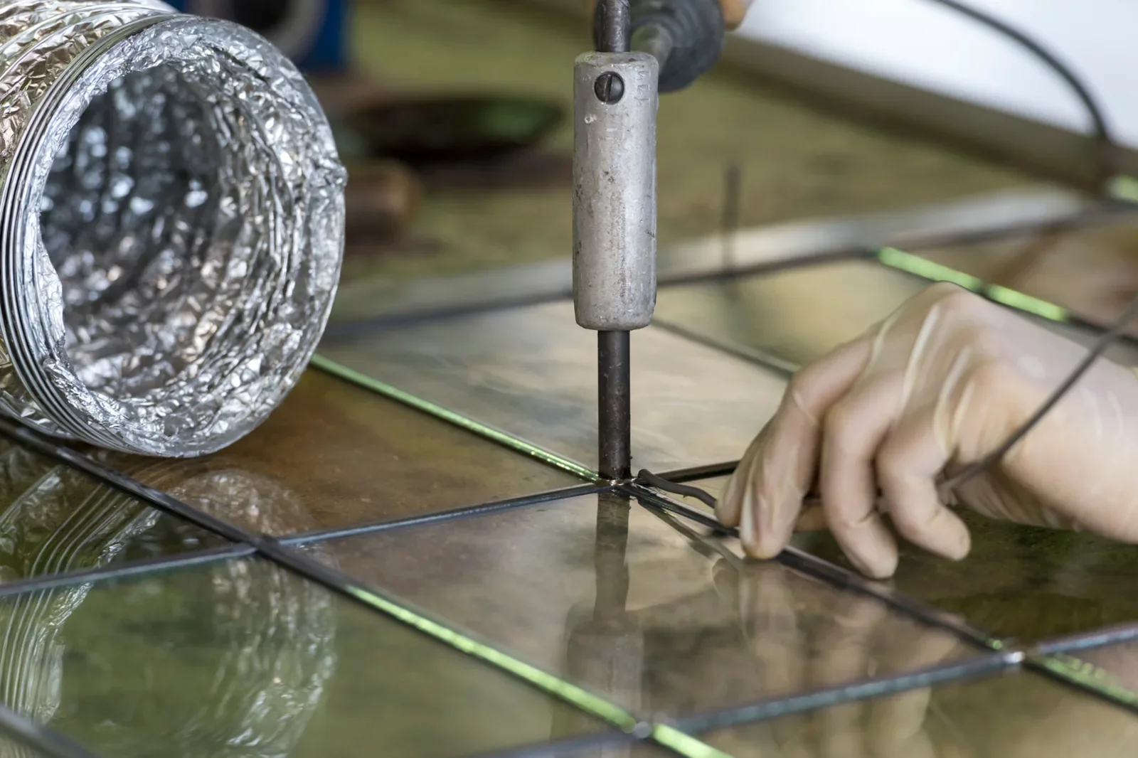 Geste artisanal lors de la fabrication et restauration d’un vitrail dans un atelier spécialisé
