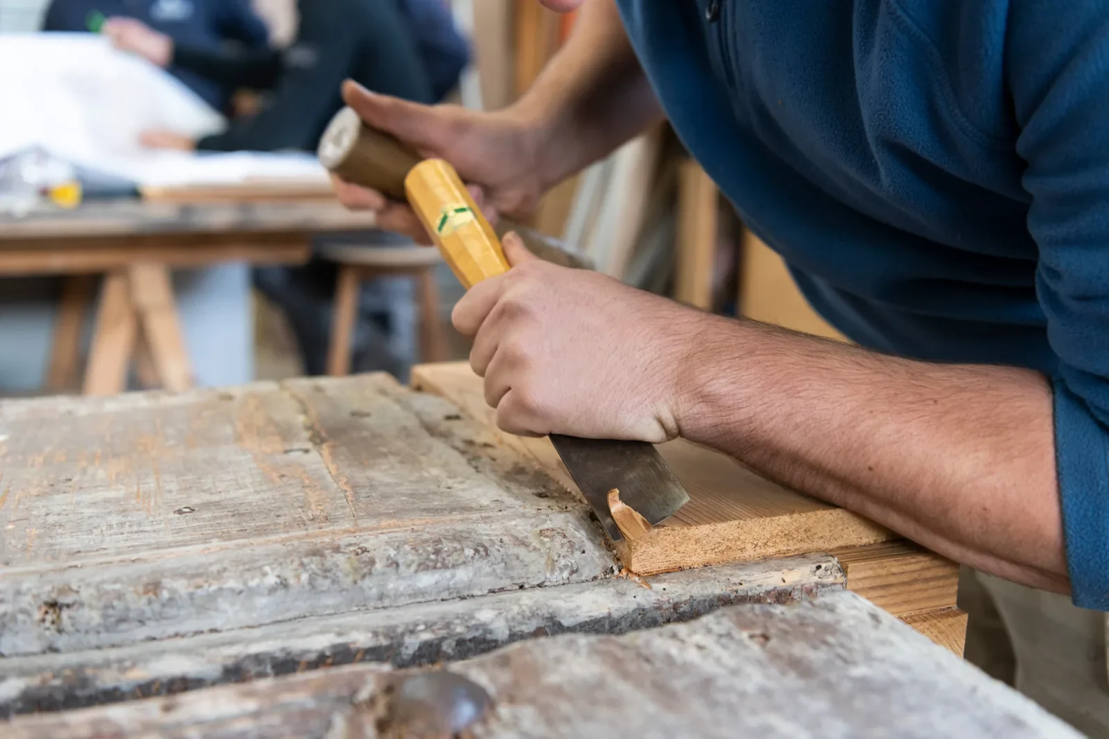 Geste d’un charpentier travaillant le bois lors d’un chantier de restauration du patrimoine