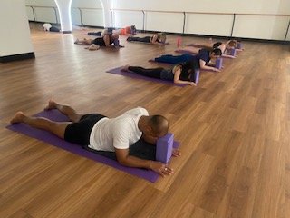 Grace at EMF Brisbane teaching a group of people practicing yoga on mats in a studio