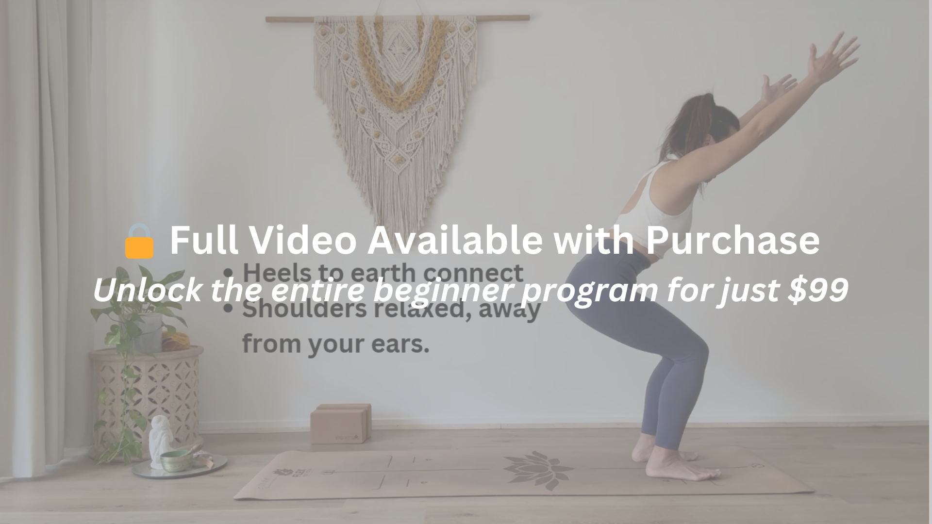Brisbane Yoga Teacher practicing Chair's Pose in a bright room, squatting with arms extended overhead on a yoga mat. Decor includes a macrame wall hanging, a plant on a side table, and a small statue.