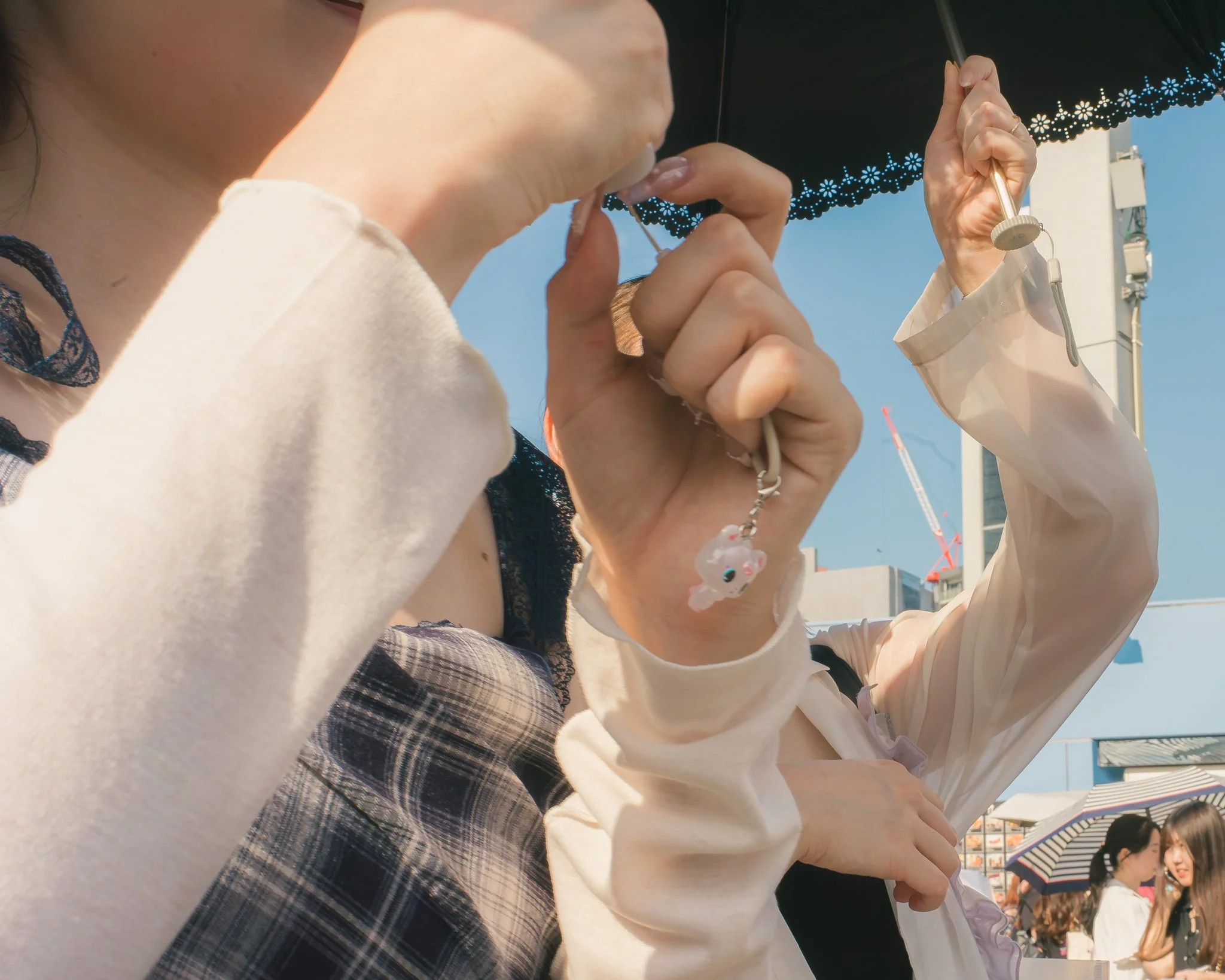 A group of people sitting outdoors under umbrellas on a sunny day, engaged in conversation.