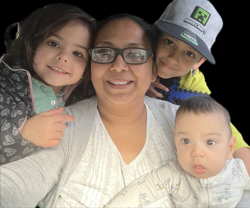 A smiling woman with glasses taking a selfie with three children around her, two boys and a girl, all appearing happy and close together.