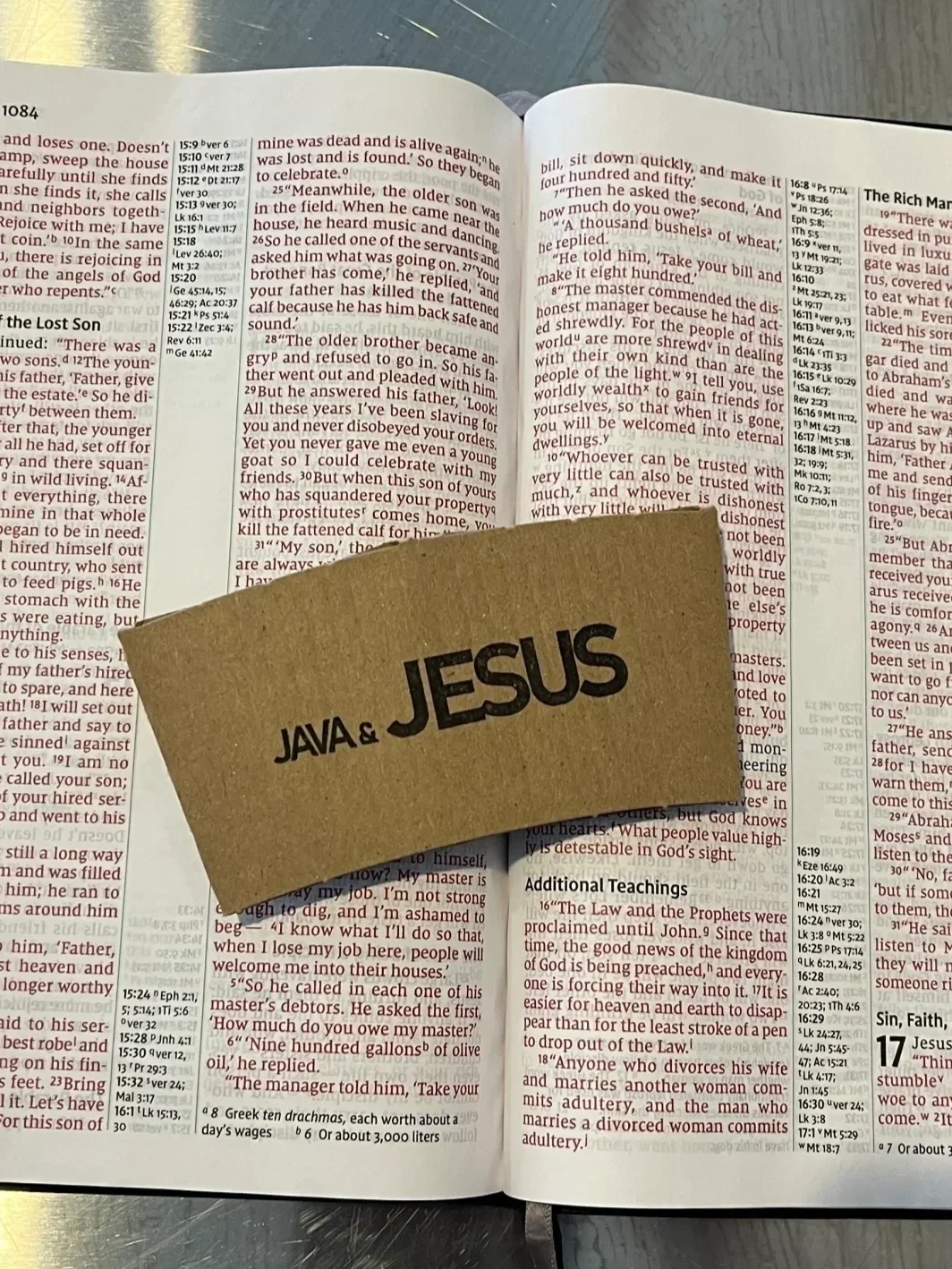 Open Bible with a brown paper card on top that says "JESUS" and "JAVA &" in bold black letters.