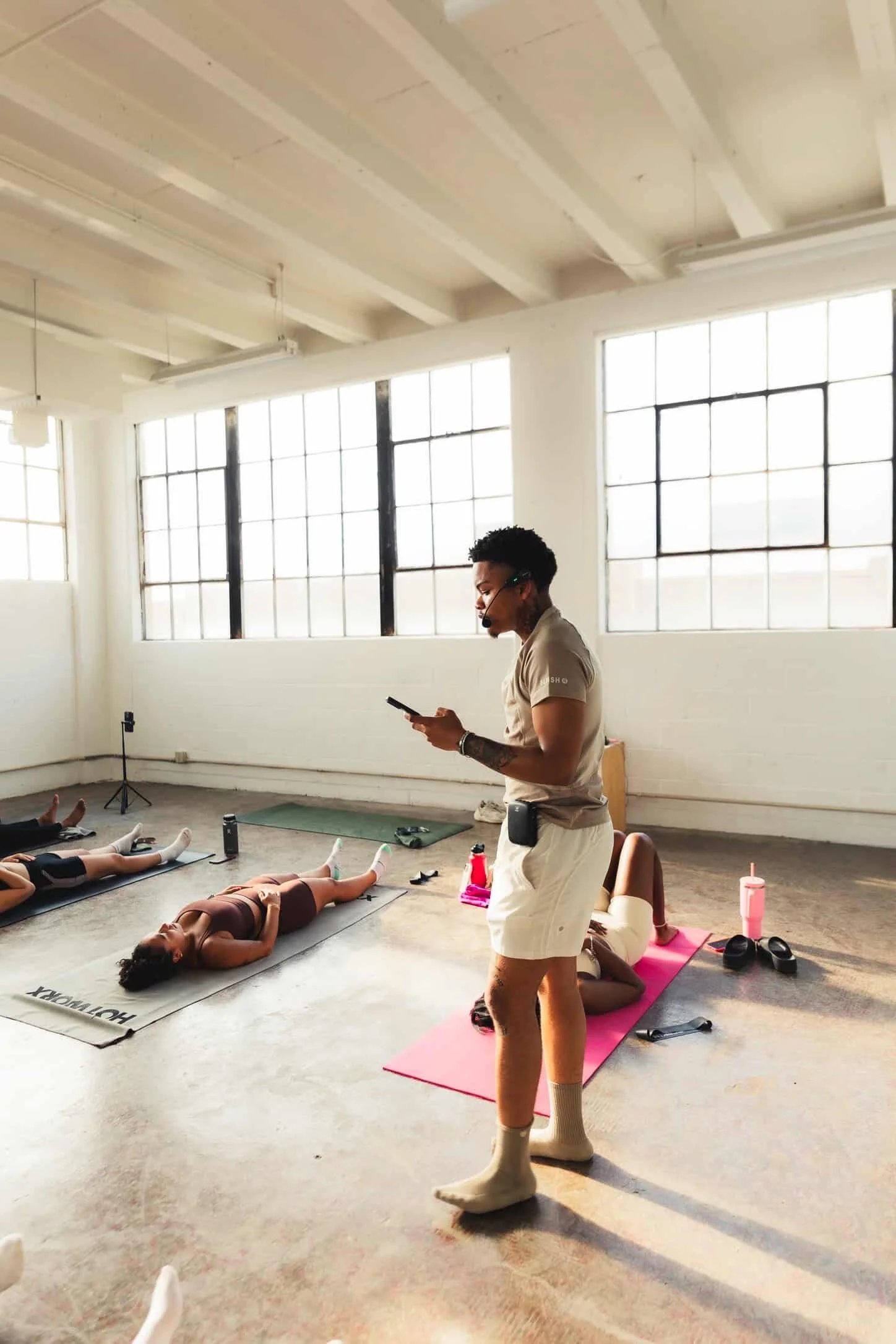 A woman with curly black hair, glasses, and a bright smile, wearing a striped shirt and layered necklaces.