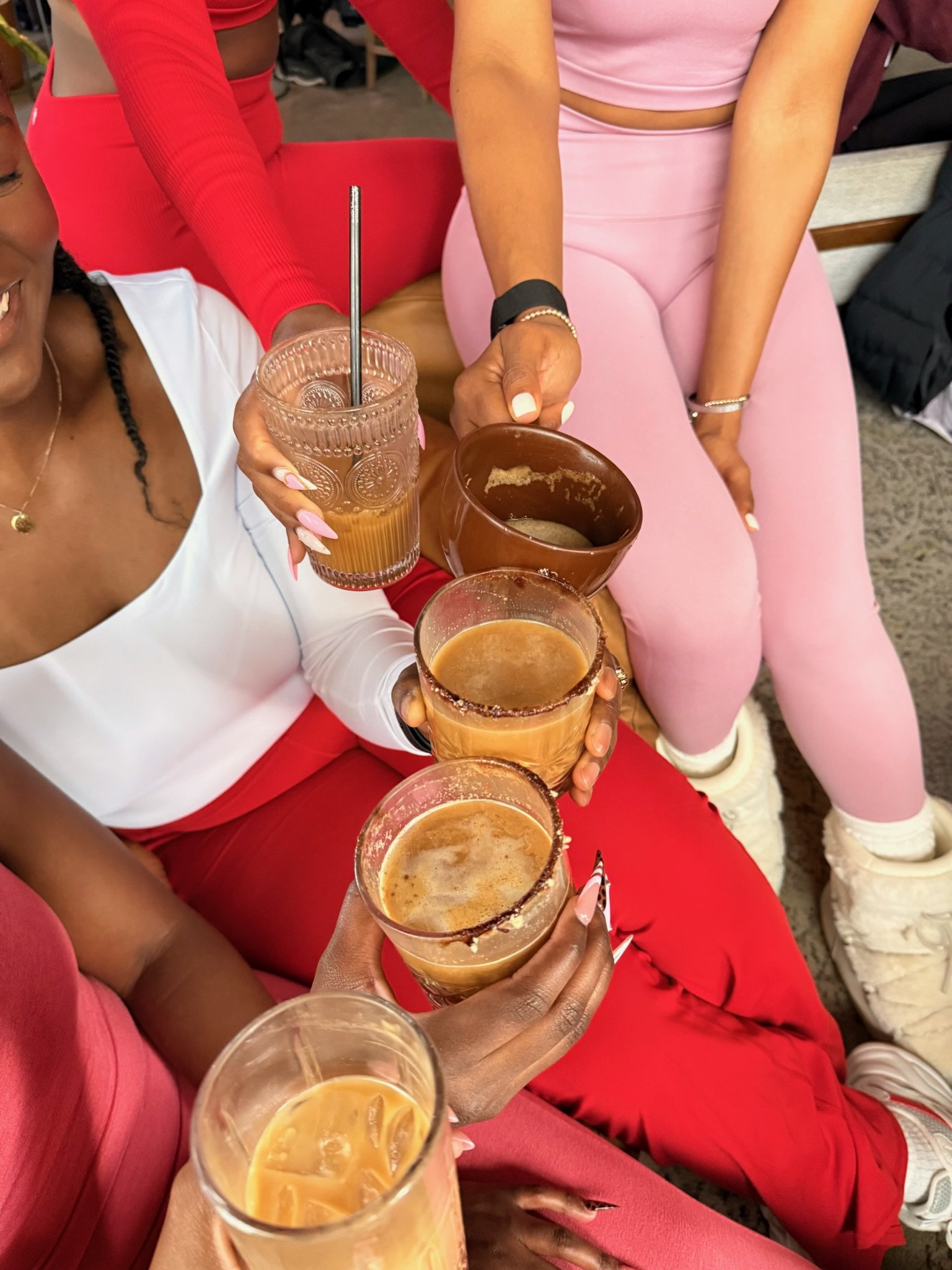 A woman with a black head wrap doing a stretching exercise on a yoga mat inside a store, with other people also stretching in the background.