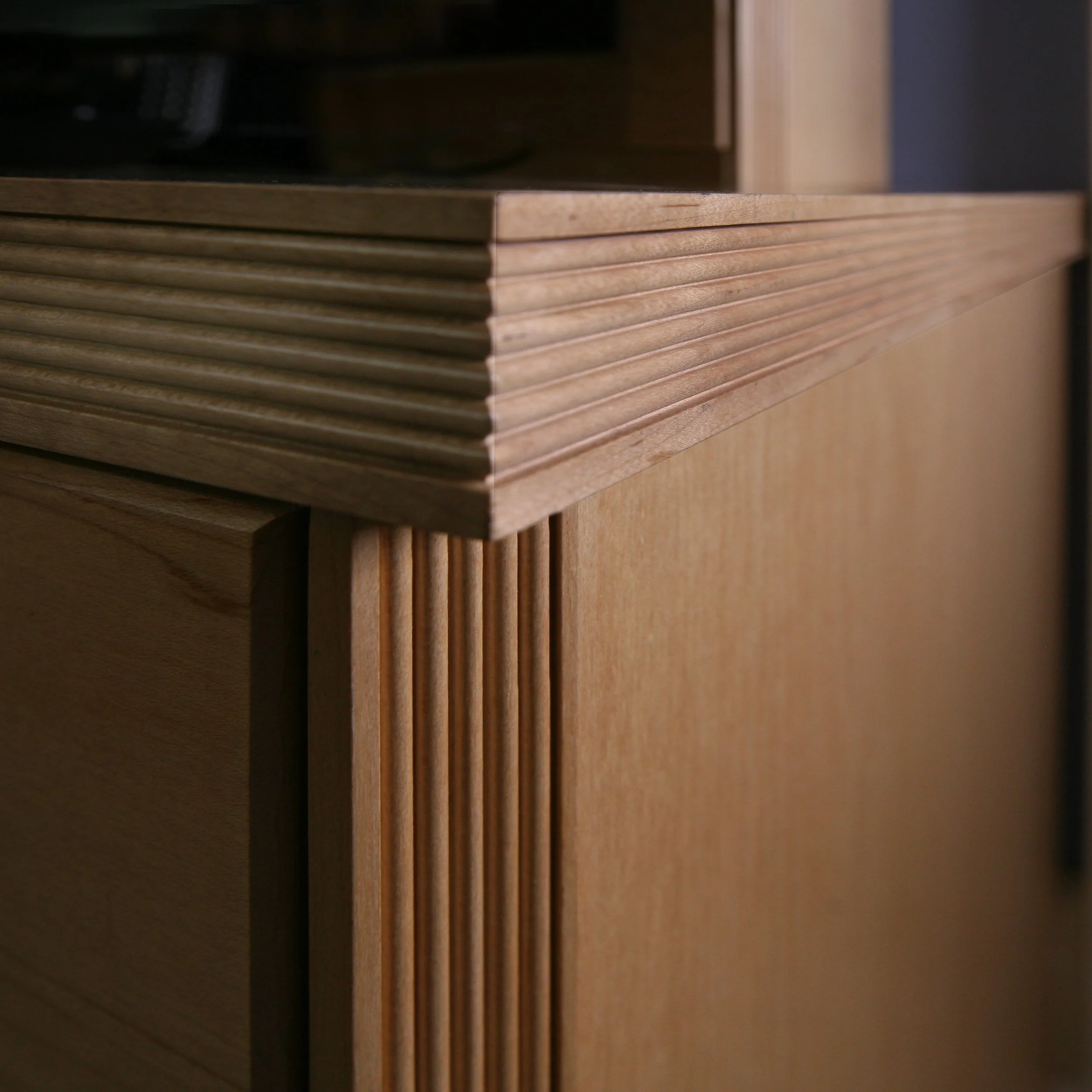 Close-up of wooden furniture corner, showing detailed craftsmanship and layered design.