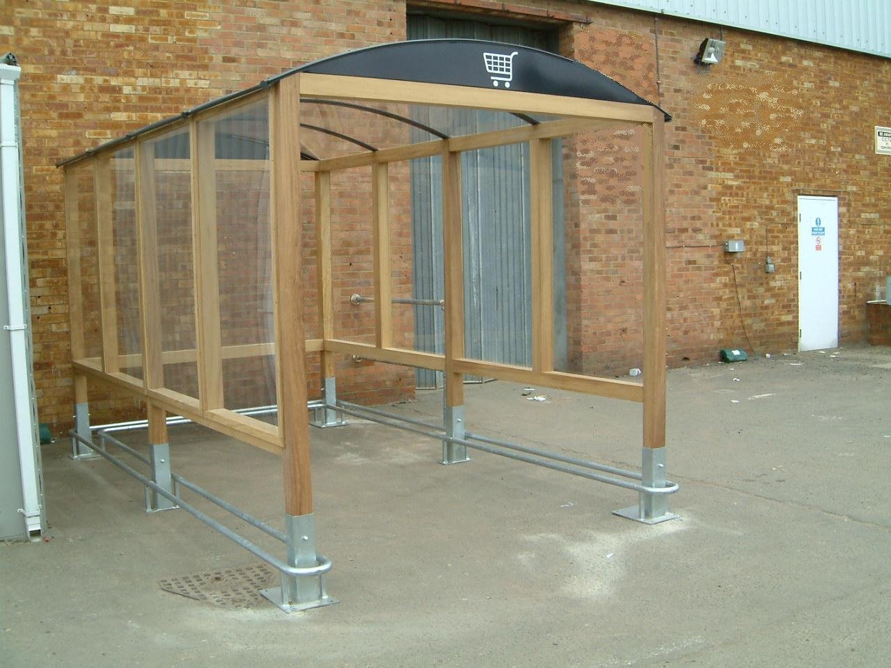 A partially constructed outdoor wheelchair ramp with a wooden frame and metal supports, situated against a brick building.