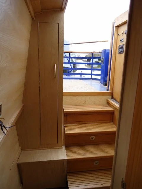 Wooden stairs leading up to a door with a blue railing outside.