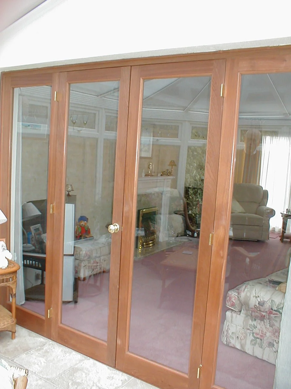 Living room with glass sliding doors, armchair, floral sofa, fireplace, and various decorations.