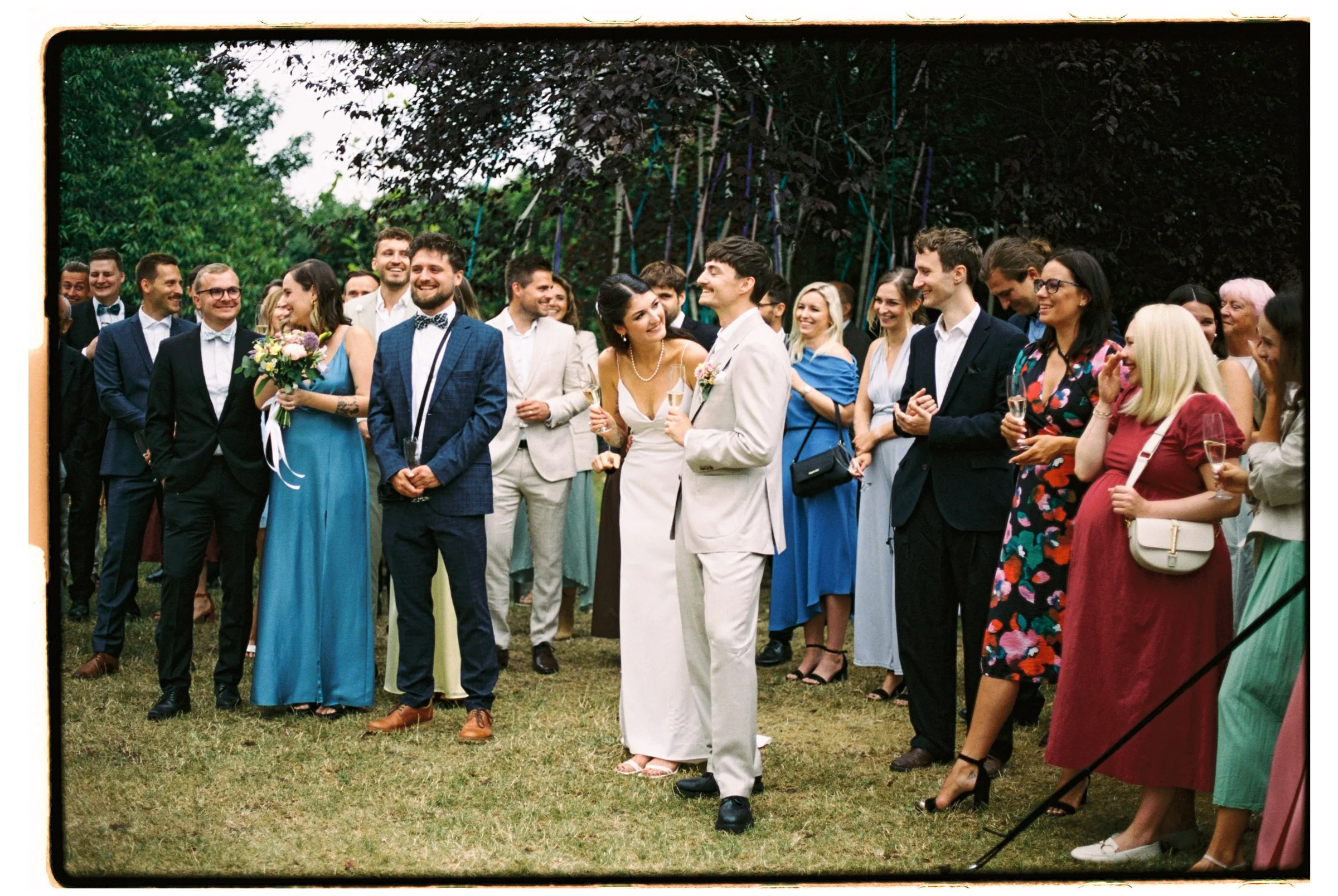 Spontánní moment novomanželů obklopených svatebními hosty, analogový fotograf