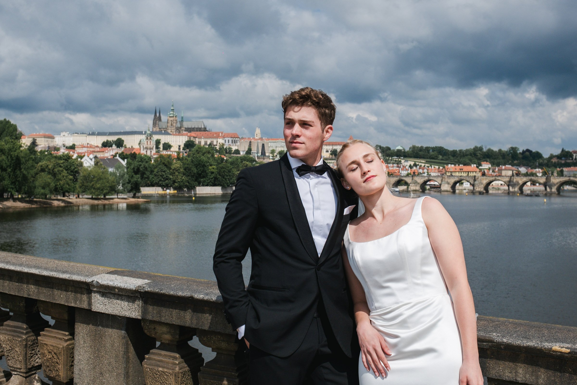 Romantic Prague elopement wedding portrait by the Vltava river with Prague Castle and Charles Bridge in the background.