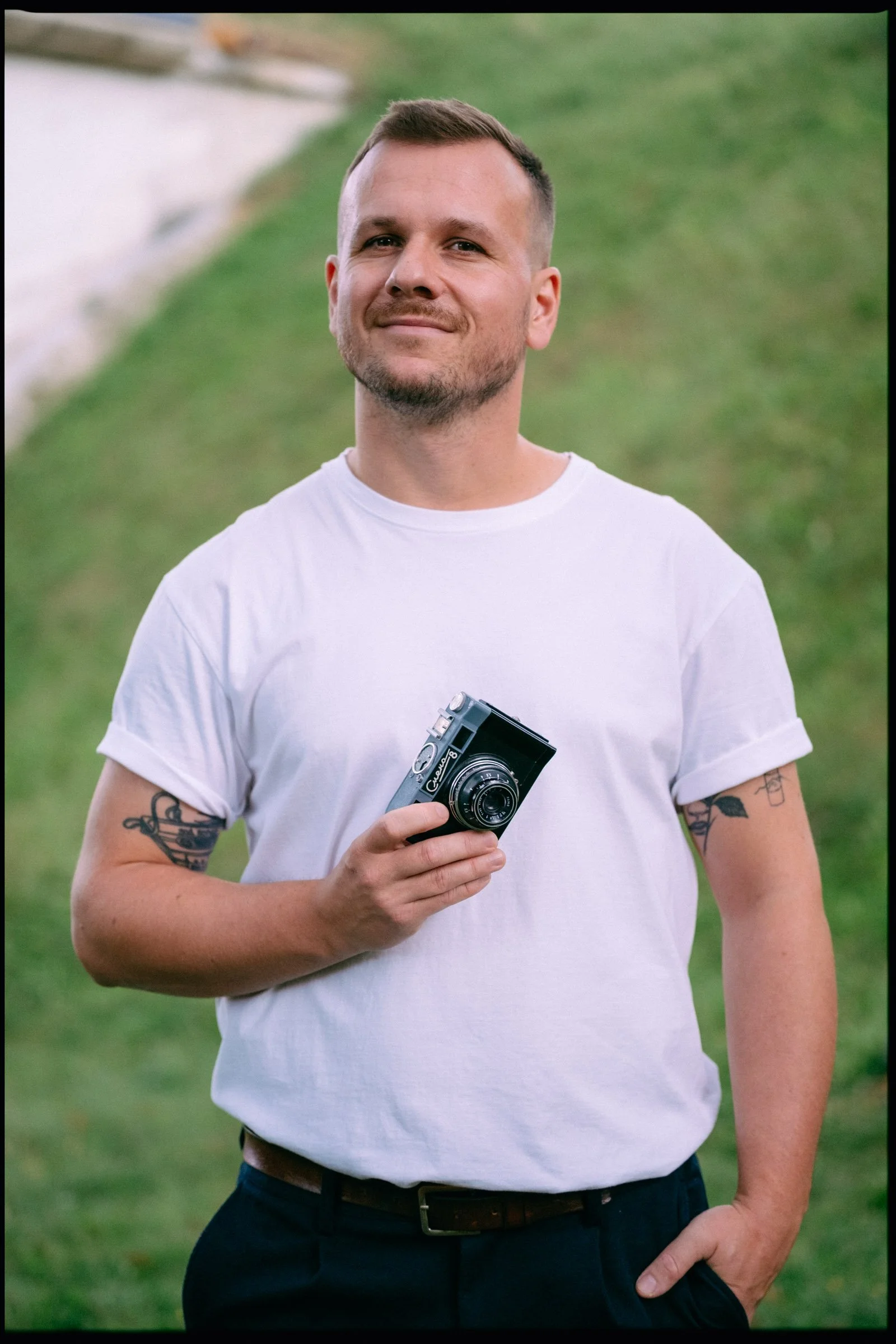 Portrét svatebního fotografa Dana Hromady z Prahy s analogovým fotoaparátem v ruce během focení v exteriéru.