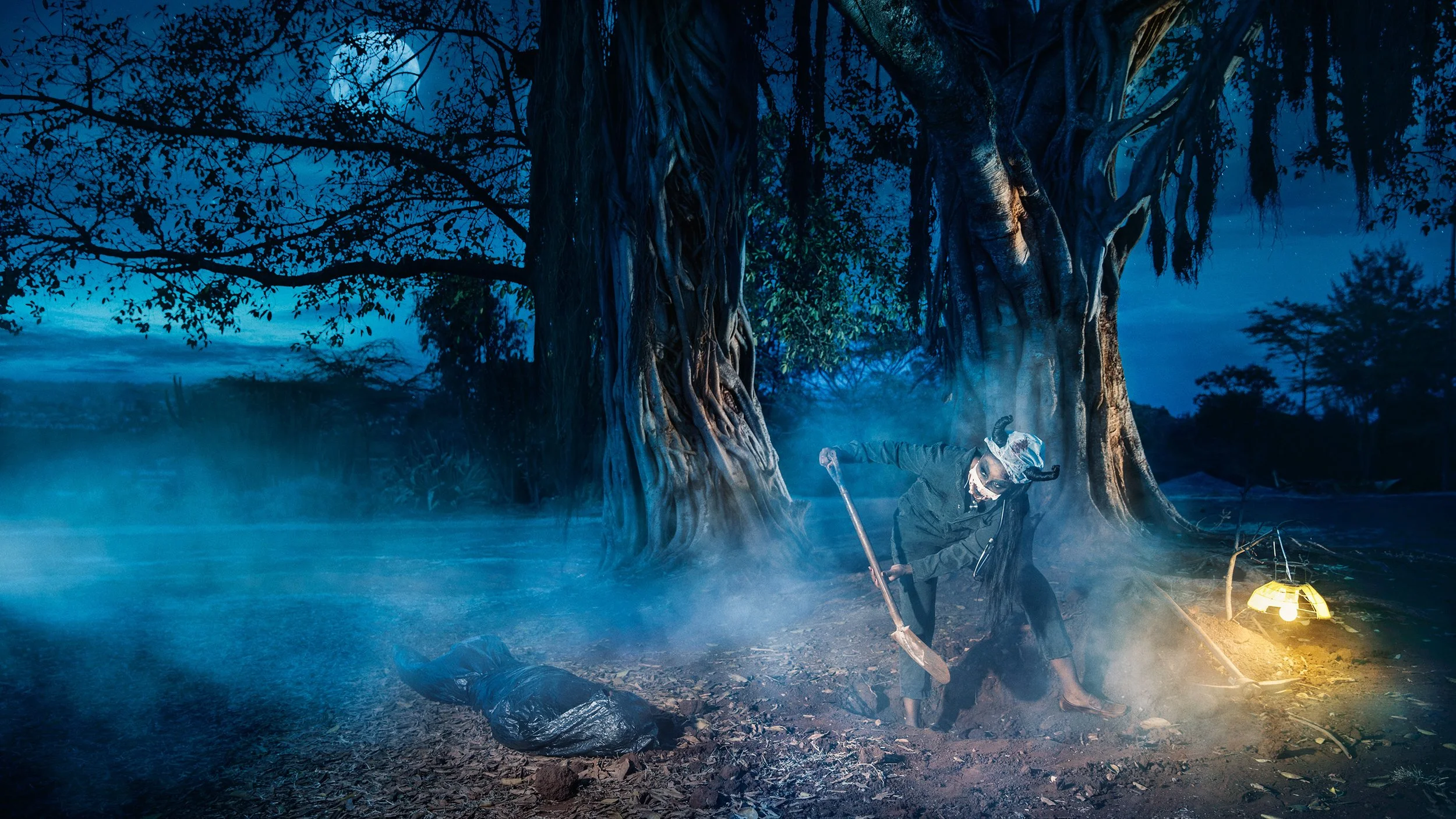 Nighttime scene with large ancient trees, a person in hunting gear, fog, and lantern light, possibly in a swamp or forest.