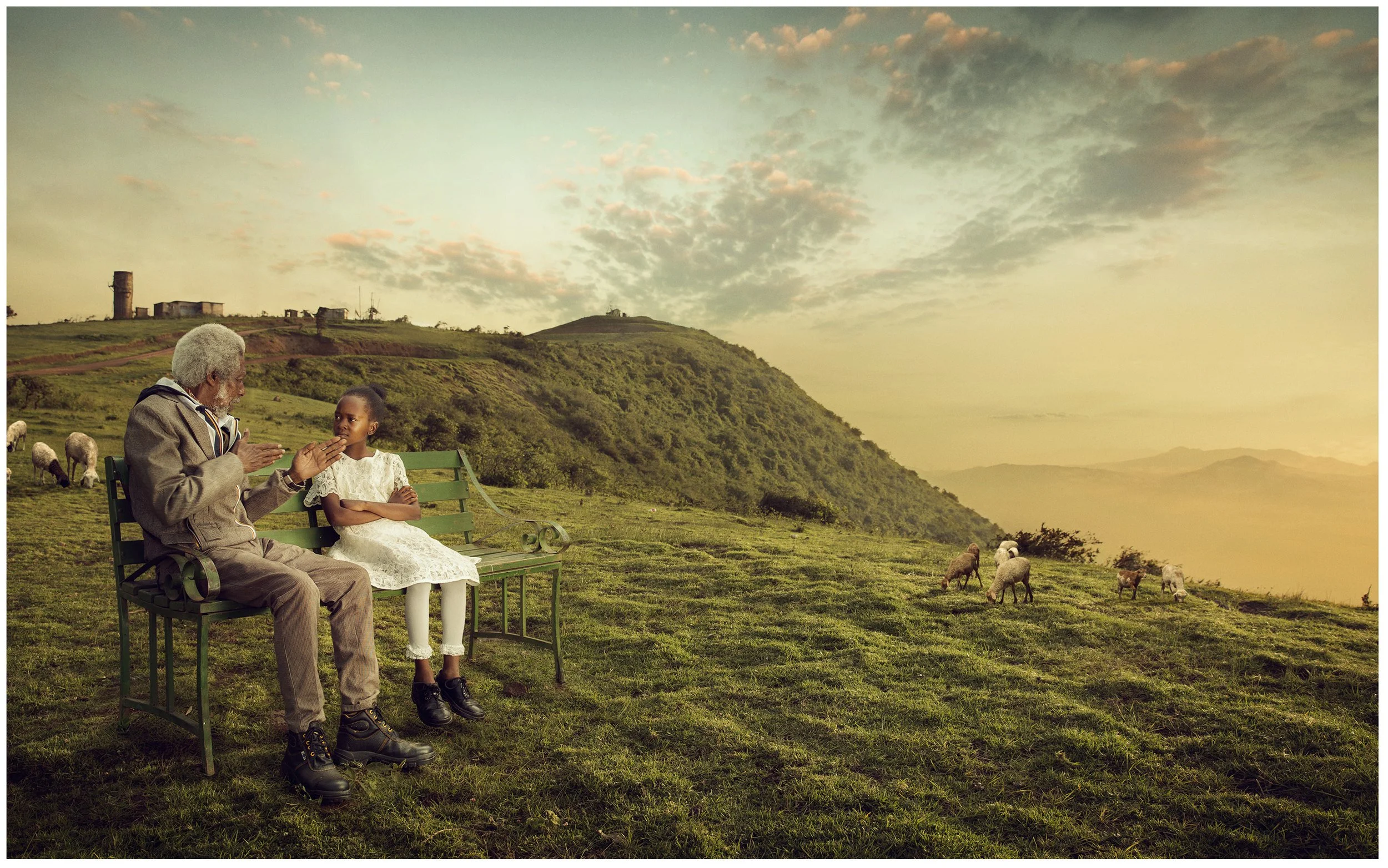 An elderly man and a young girl sit on a park bench in a grassy, hilly landscape. The man appears to be talking to the girl, who is listening with her arms crossed. Sheep are grazing nearby, and in the background, there are hills, a small building, and a tower under a partly cloudy sky.