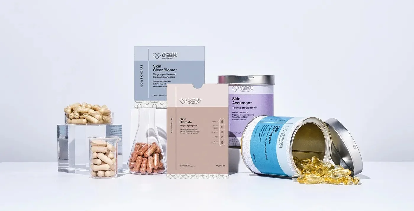 Various supplement bottles and capsules on a white surface, including jars of pills and capsules with labels related to skin health.