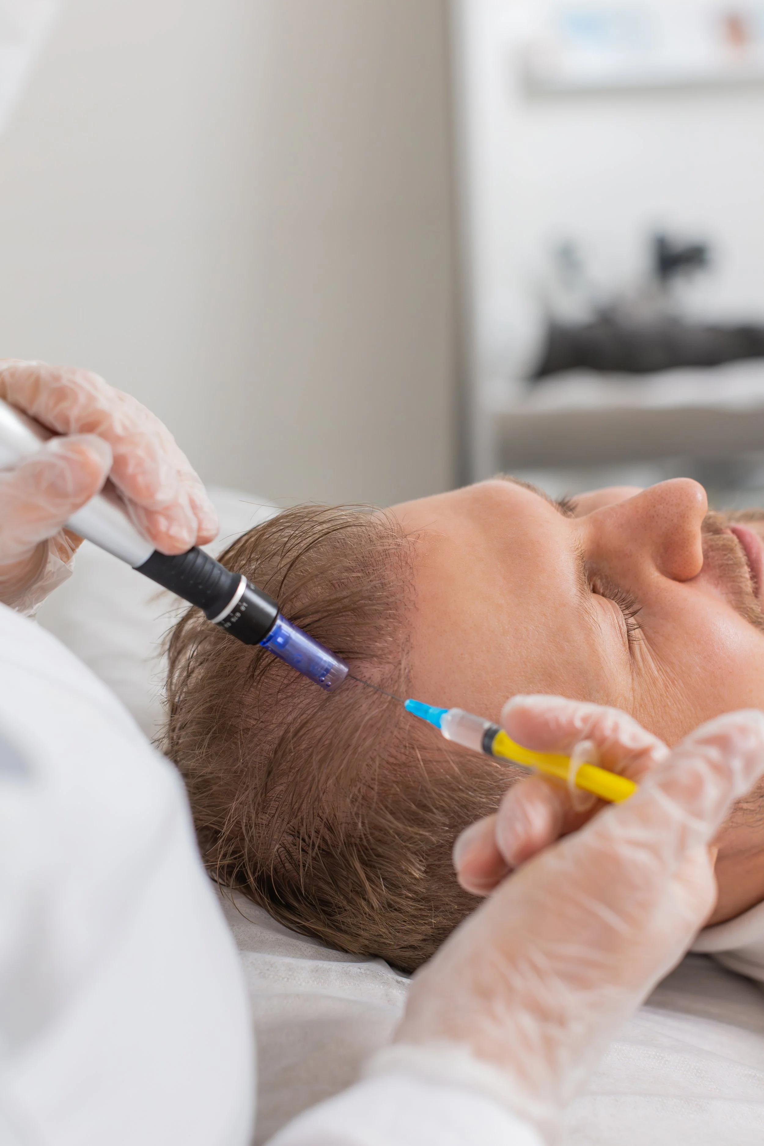 A person undergoing a medical or cosmetic procedure with a machine emitting pink light, lying on a treatment bed covered with a white towel.