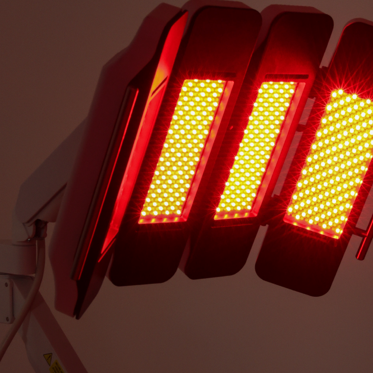 Close-up of a red LED red light therapy device with multiple rectangular panels emitting bright red light.