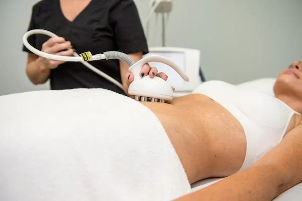 A medical professional performing an ultrasound on a woman lying on a hospital bed.