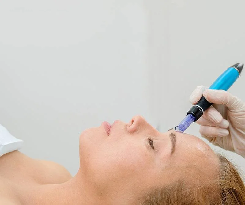 A woman receiving an injectable treatment in her forehead from a medical professional wearing gloves.