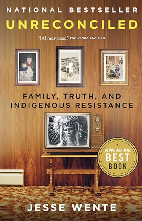 Book cover for 'Unreconciled' by Jesse Wente featuring framed photographs and an old television set displaying an Indigenous person wearing a feathered headdress, set against a wood-paneled wall with a patterned carpet.
