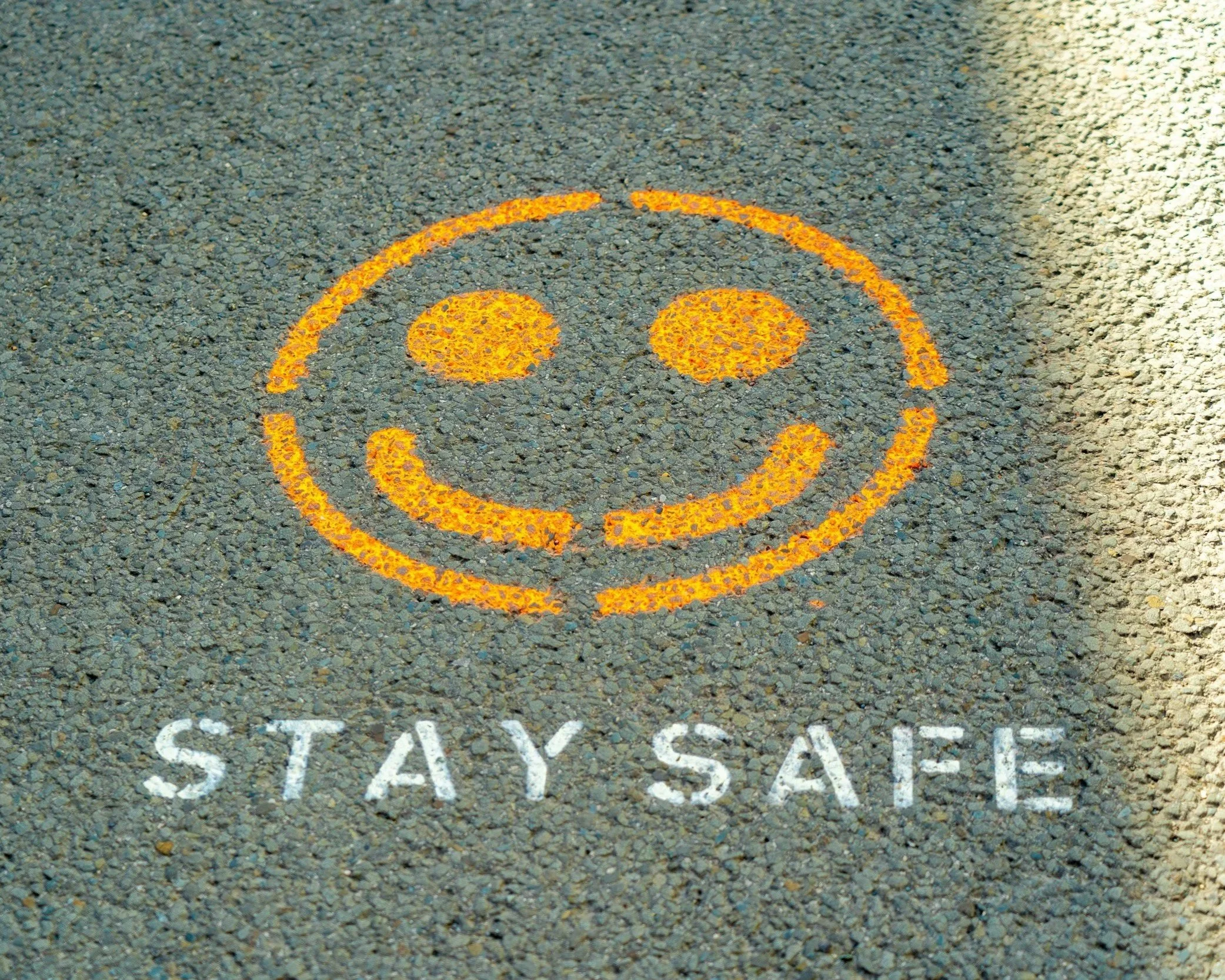 Pavement with statement, "Stay Safe" and smiley face