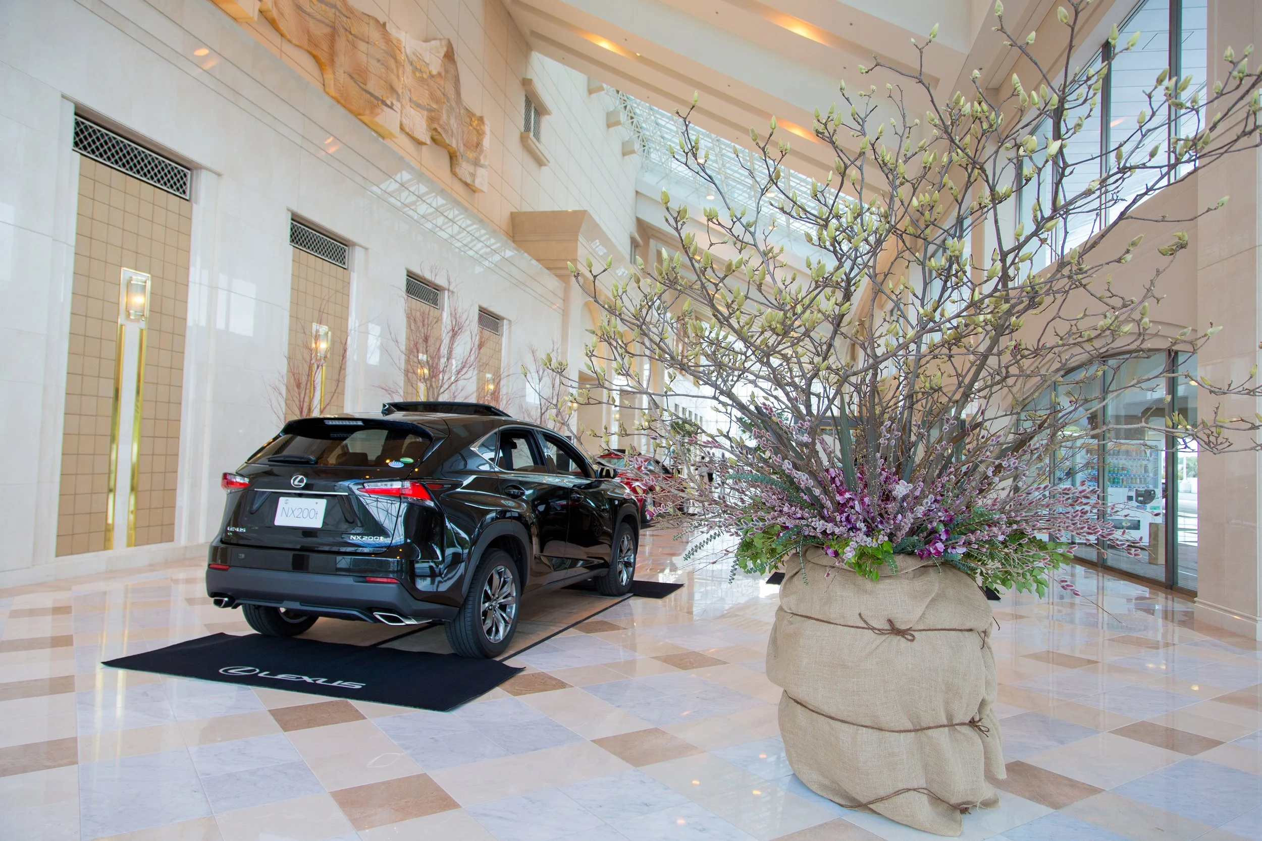 Floral atmosphere for Lexus NX200h event, featuring large-scale spring branch arrangements in a luxury automotive showroom.