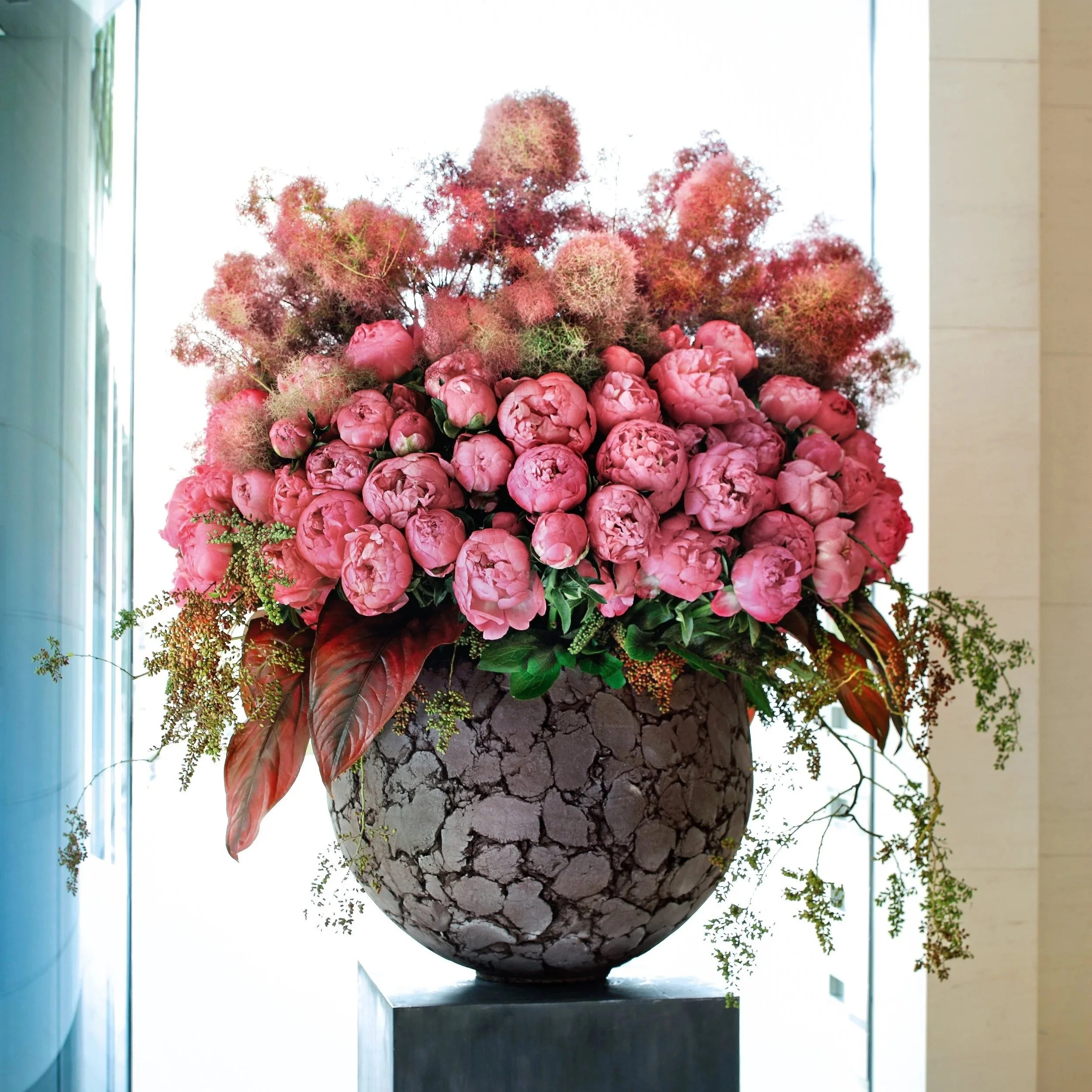 Daniel Ost grand floral arrangement with pink peonies and smokebush in sculptural vase.