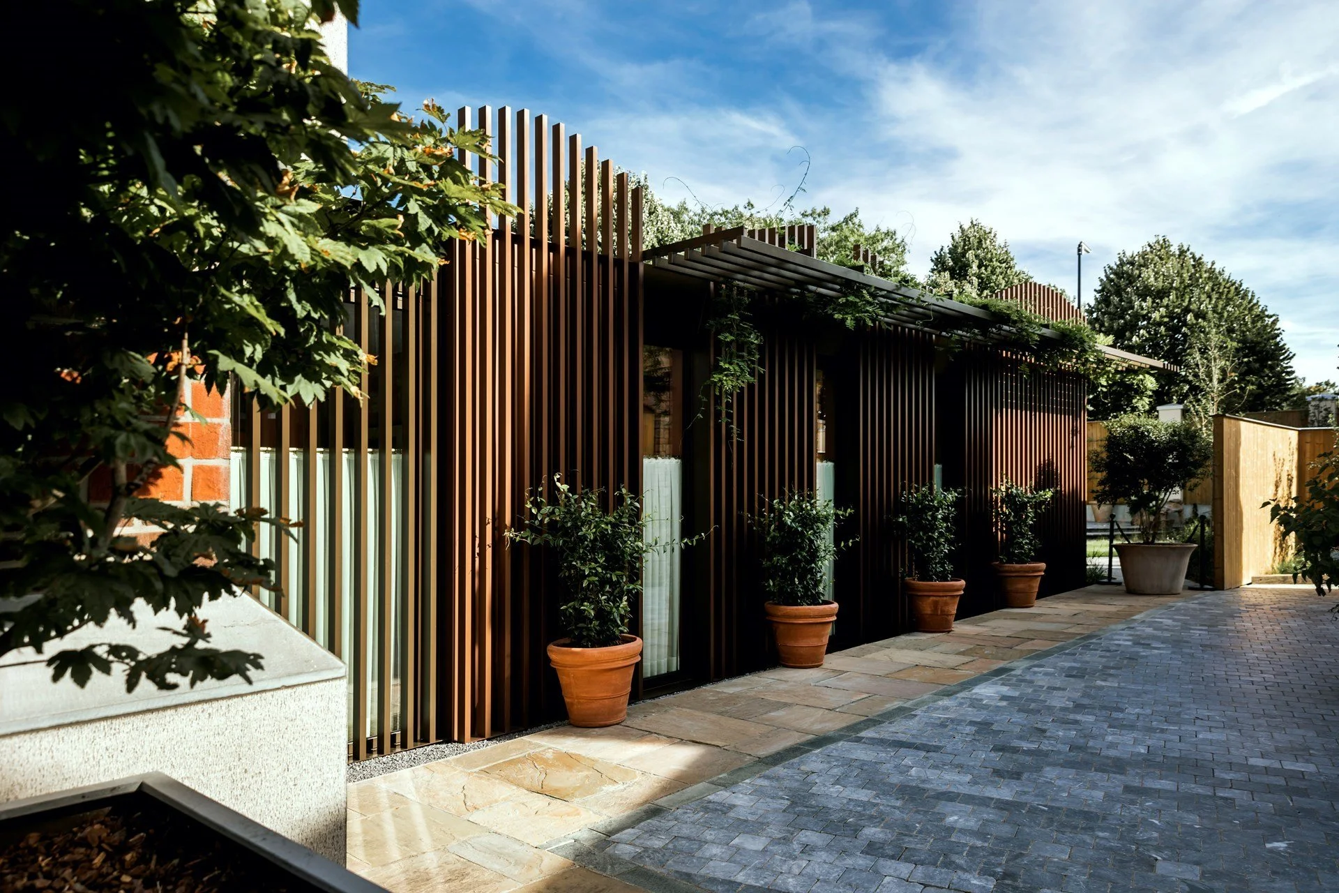 Contemporary façade design with vertical wooden slats and terracotta planters, integrating greenery into a corporate entrance.