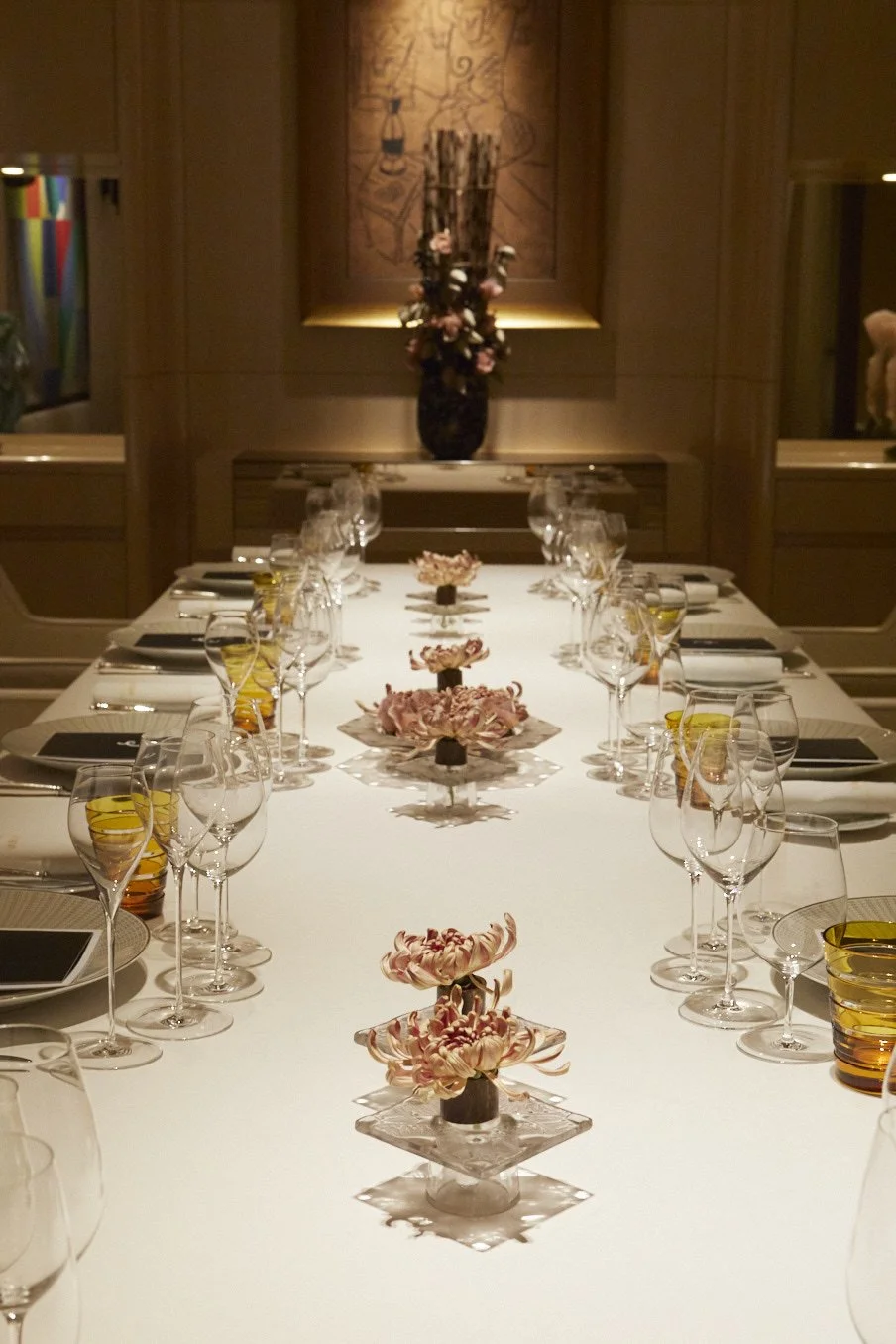 Private dining room floral styling with chrysanthemum table accents arranged in crystal holders along a luxury banquet table.