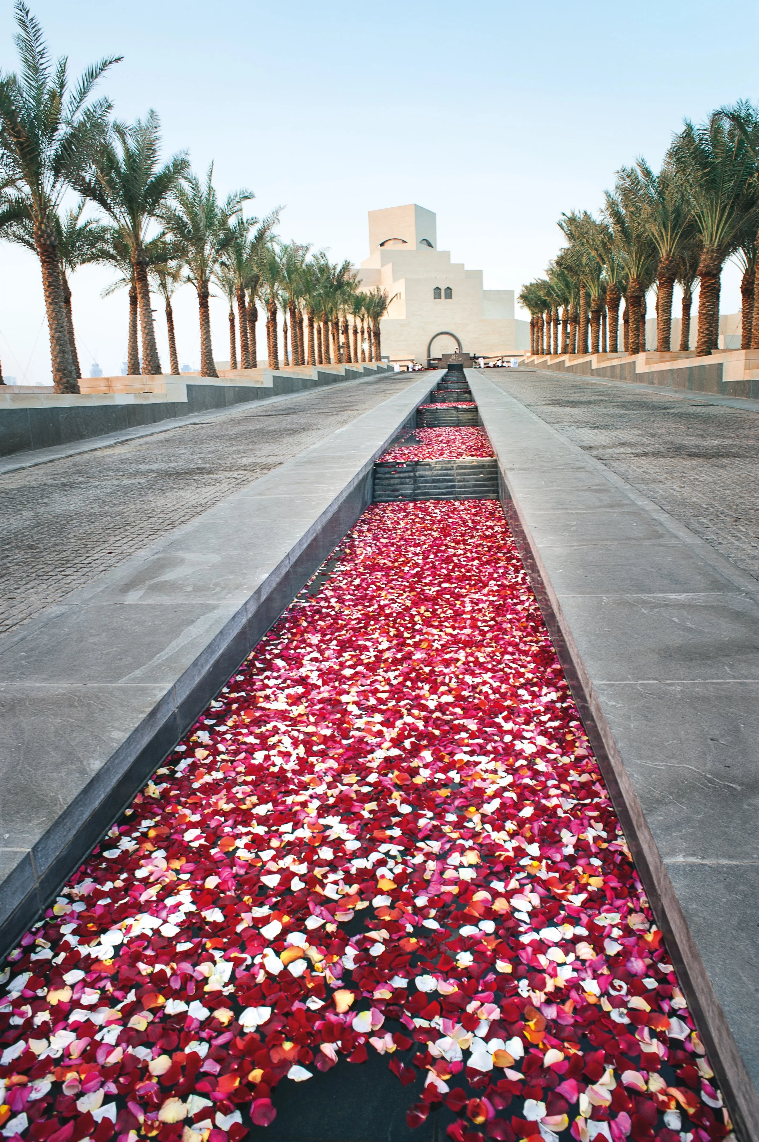 Luxury corporate event installation with rose petals floating in water feature at Museum of Islamic Art Doha.