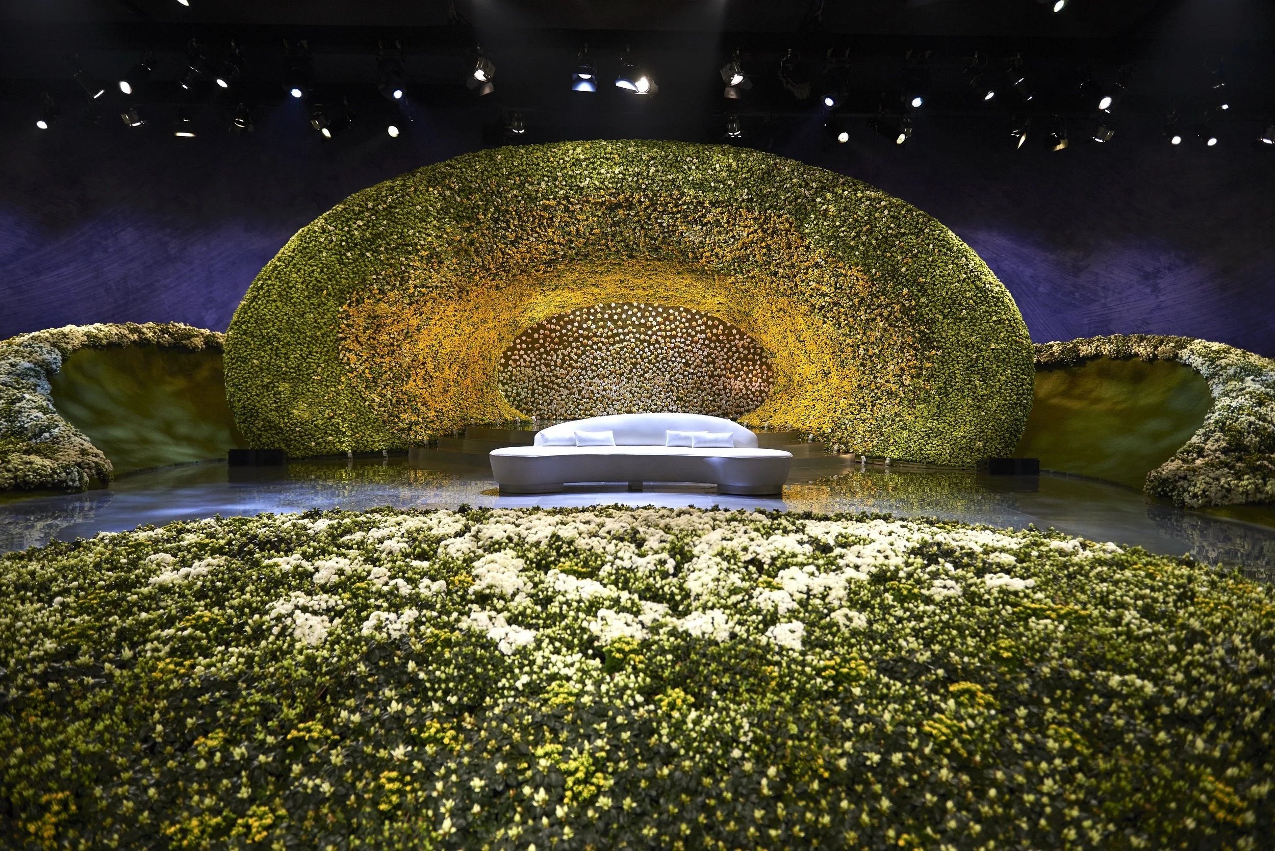 Luxury wedding stage with immersive yellow and green floral arch installation by Daniel Ost.