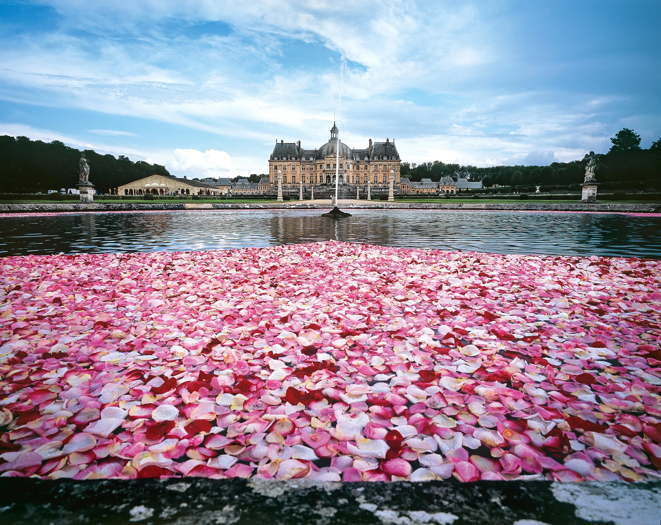Romantic wedding celebration with thousands of rose petals floating on water at Château de Vaux-le-Vicomte by Daniel Ost.