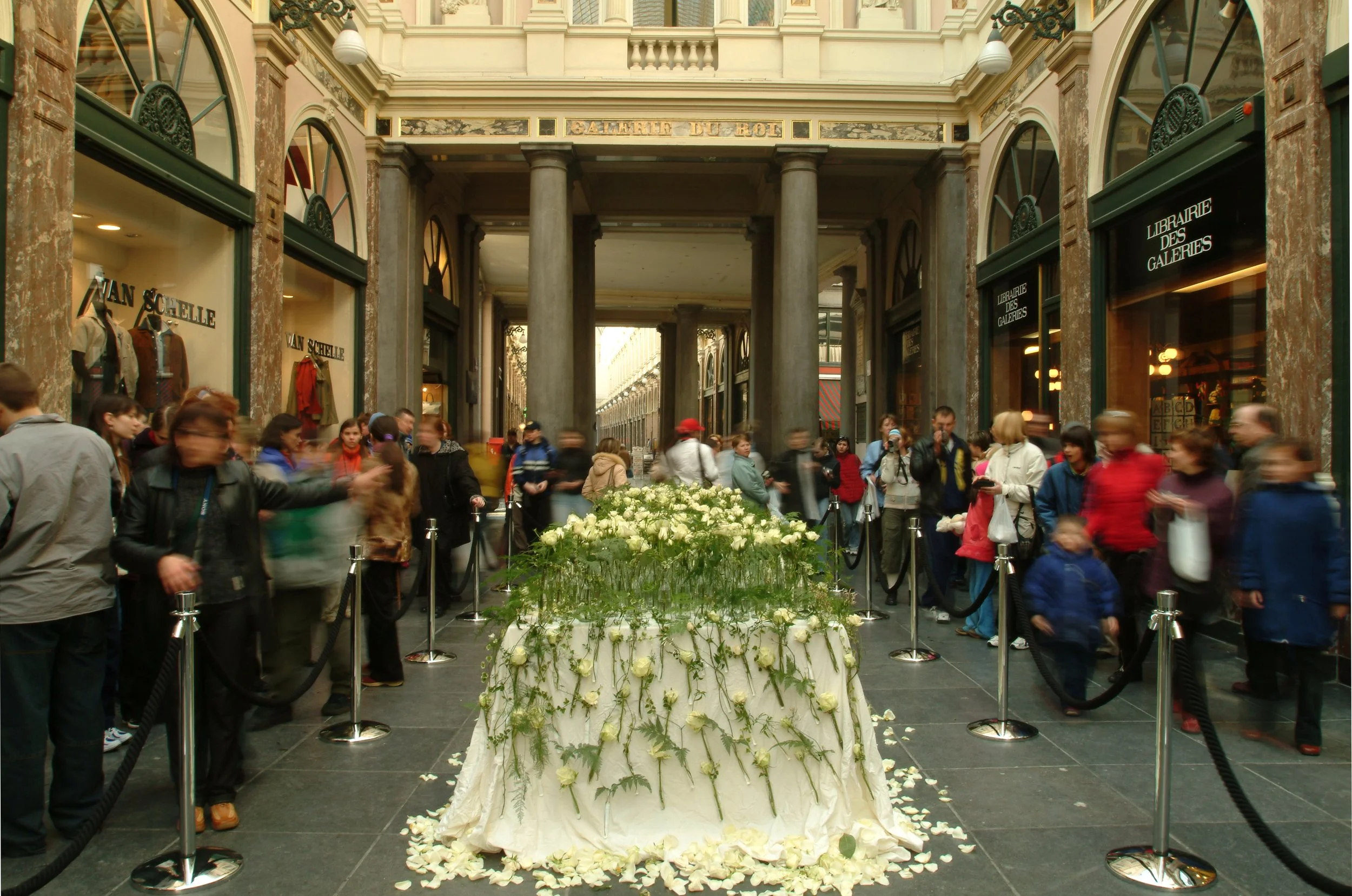 Luxury floral installation of white roses in Galeries Royales Saint-Hubert Brussels, surrounded by visitors admiring the sculptural design by Daniel Ost.