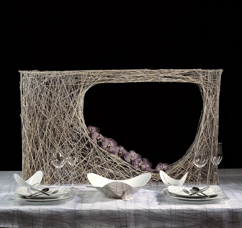 Modern wedding table design with a sculptural twig frame and purple orchids, adding artistry and intimacy to a luxury dining experience.