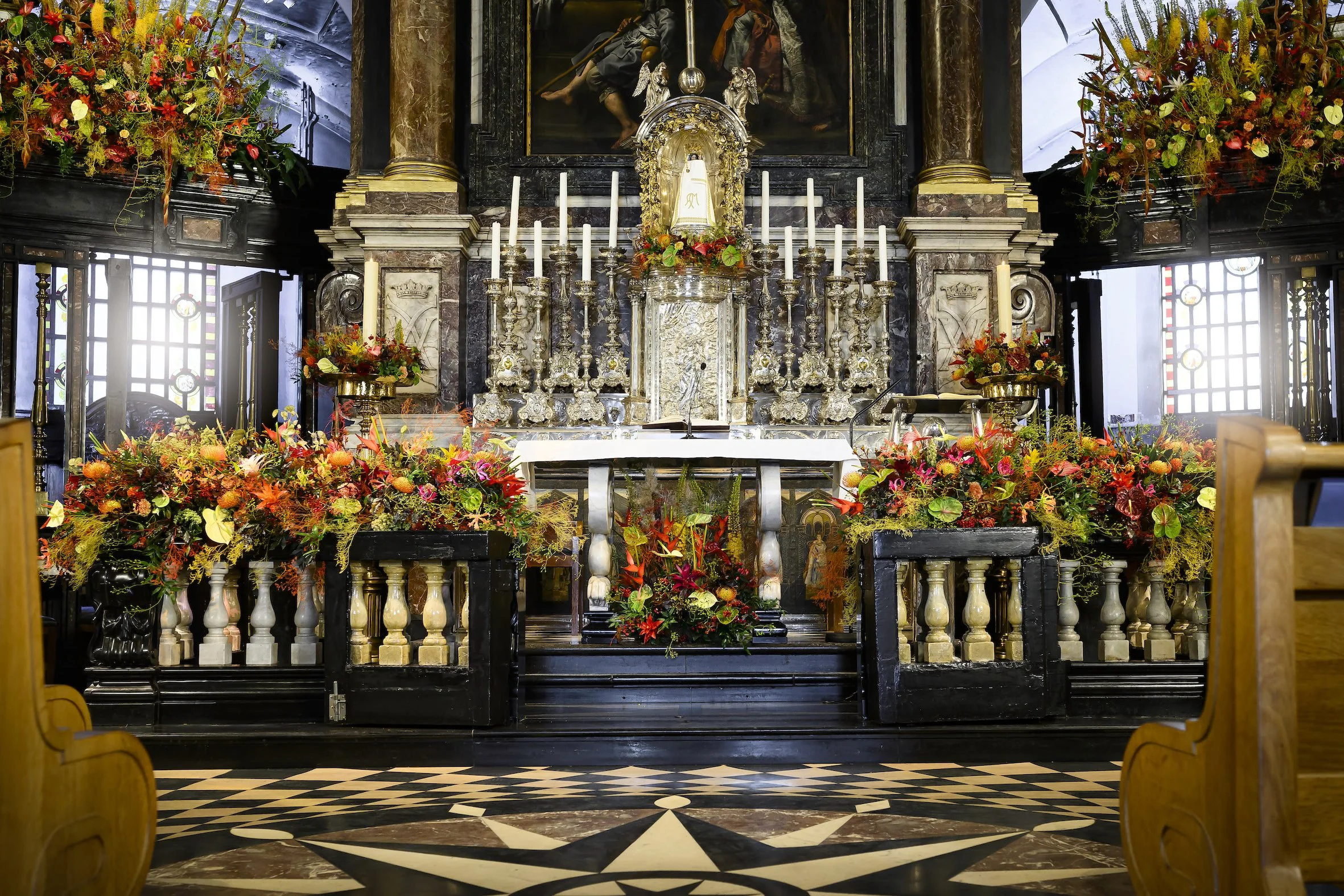 Baroque church altar decorated with vibrant floral arrangements in red, orange, and yellow, enhancing the historic architecture with luxury floral artistry.