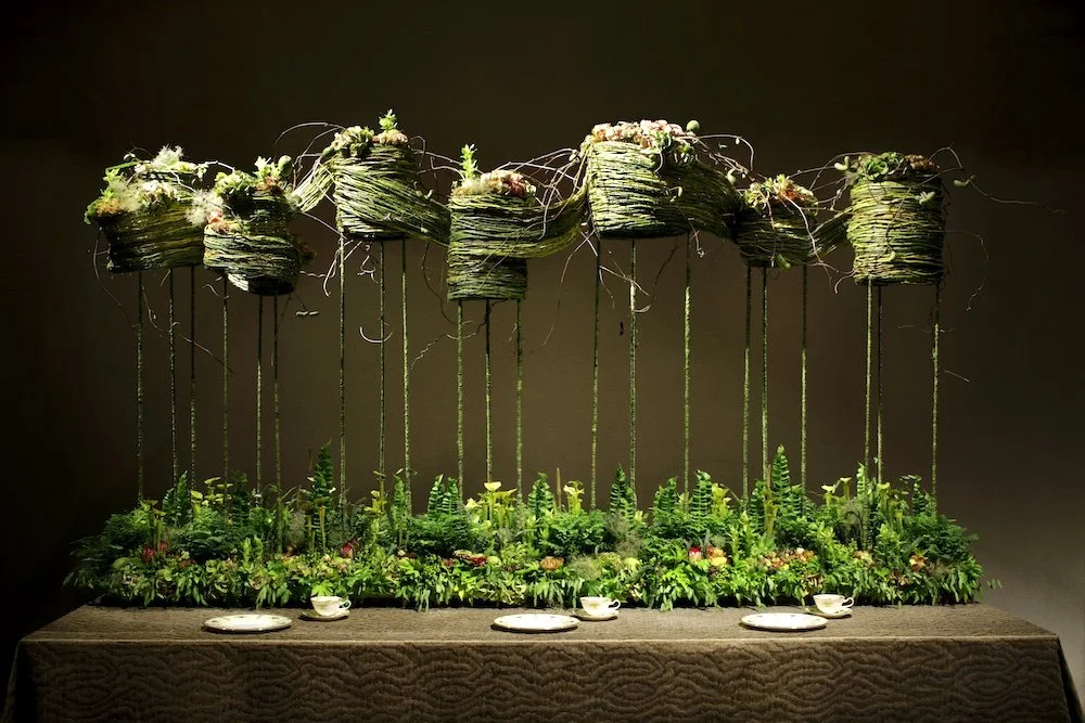 Dramatic long table centerpiece with floating woven baskets and lush greenery below, creating an enchanting and intimate wedding atmosphere.
