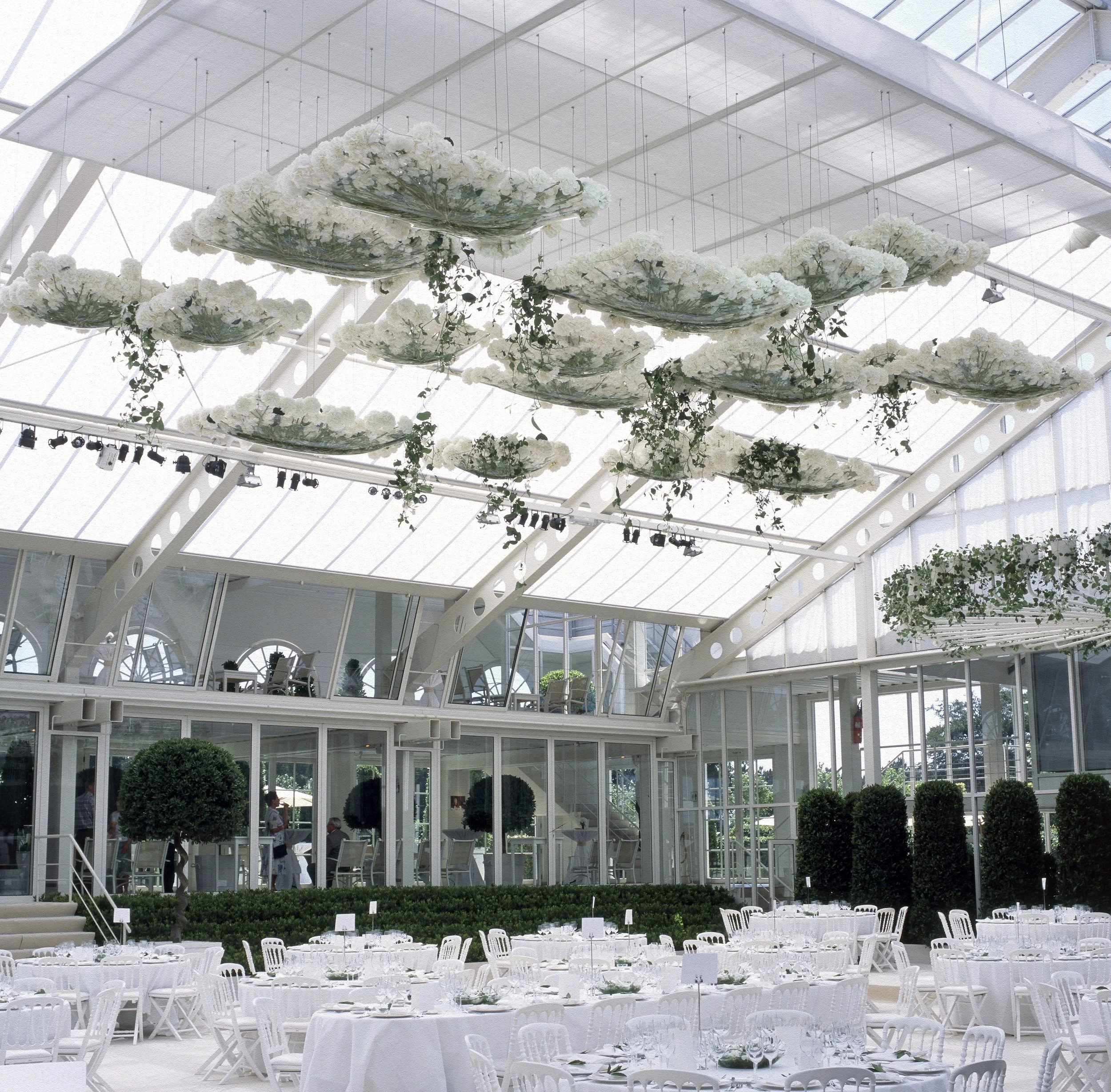 Luxury wedding reception with white floral ceiling clouds and elegant round tables designed by Daniel Ost