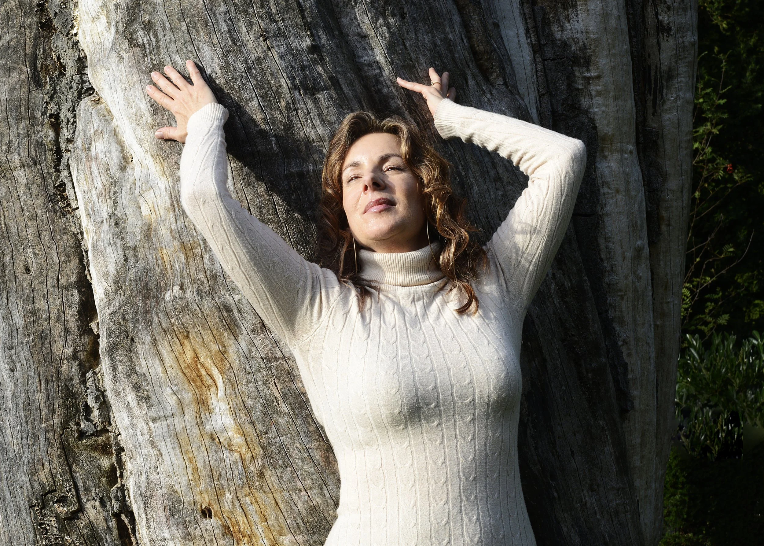 Frederikke Darkner leaning against a tree, grounded and present in nature.