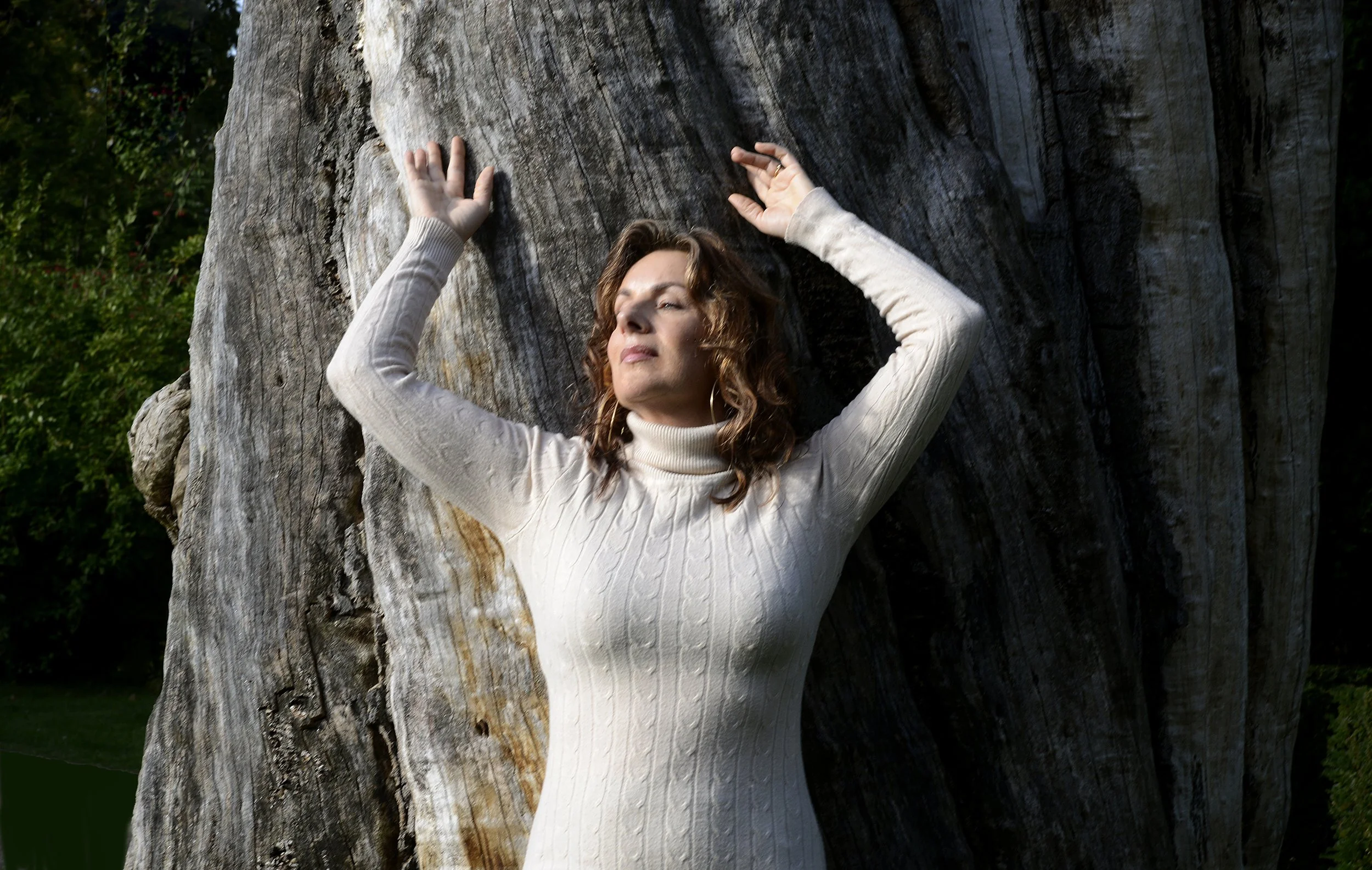 Frederikke Darkner resting against a tree, connected to earth and stillness.