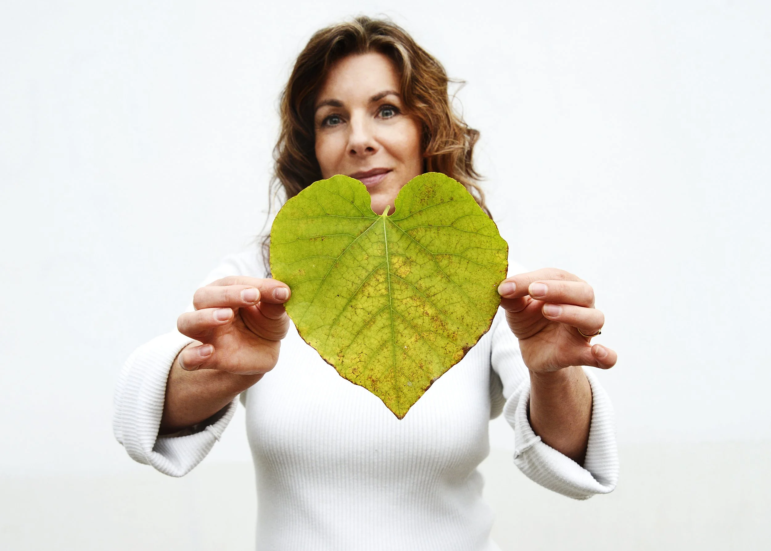 Frederikke Darkner holding a heart-shaped leaf in a moment of stillness.