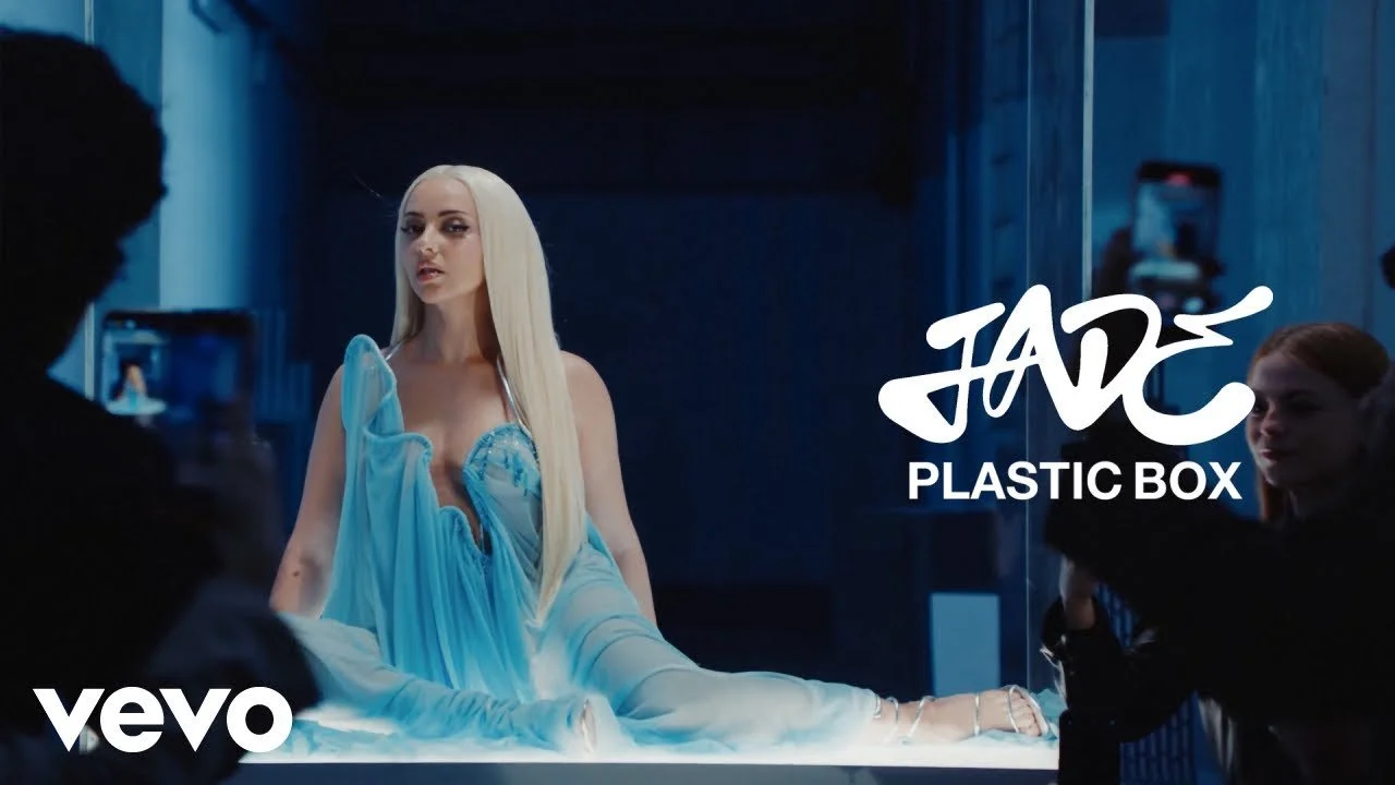 Under the direction of India Harris, the “Plastic Box” video uses glass-box metaphor and staged gallery moments to visualize JADE’s feeling of being observed and constrained by her partner’s past. Harris balances high style with vulnerability, creati