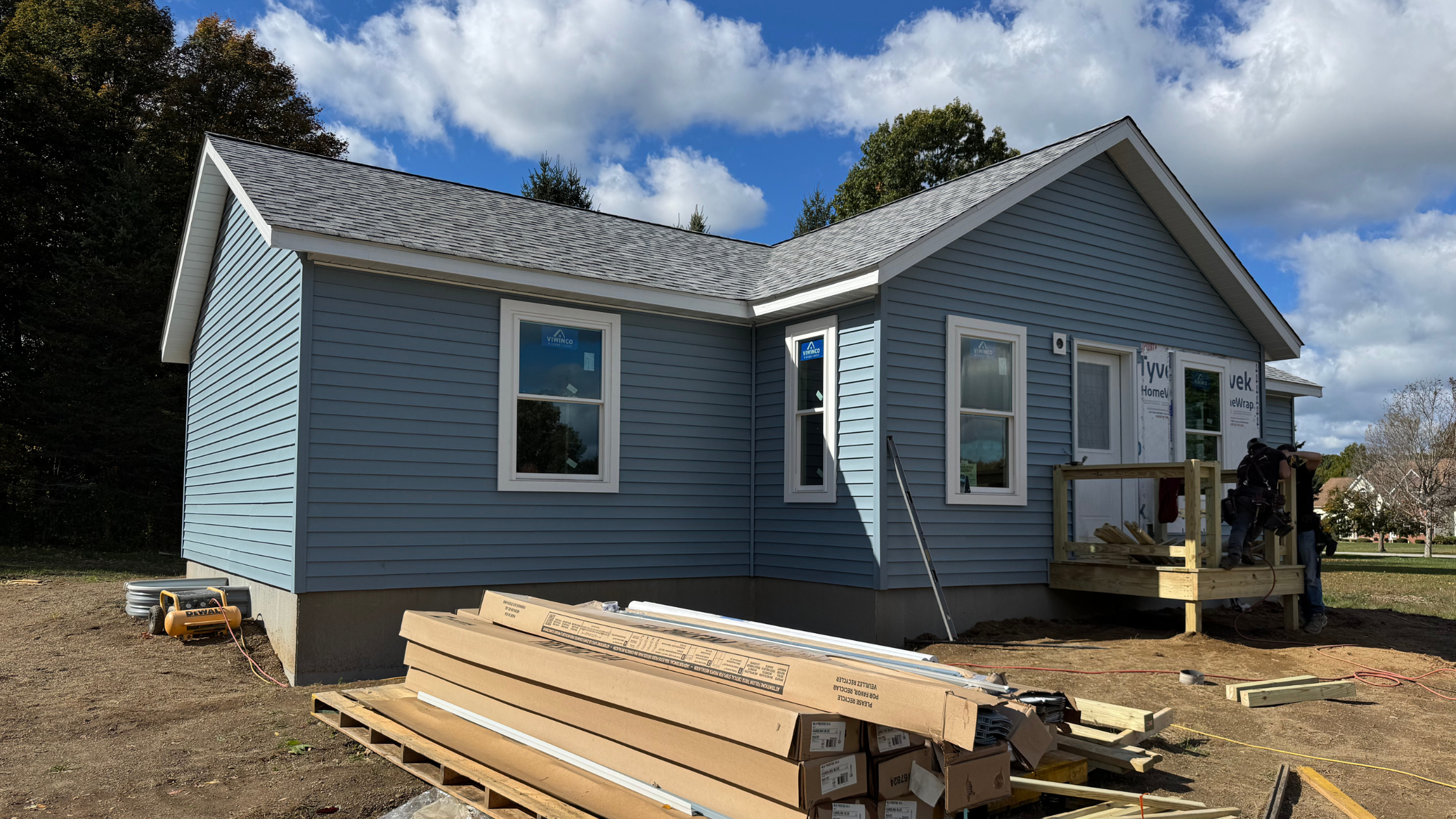 An exterior image of a grey/blue modular home in progress.