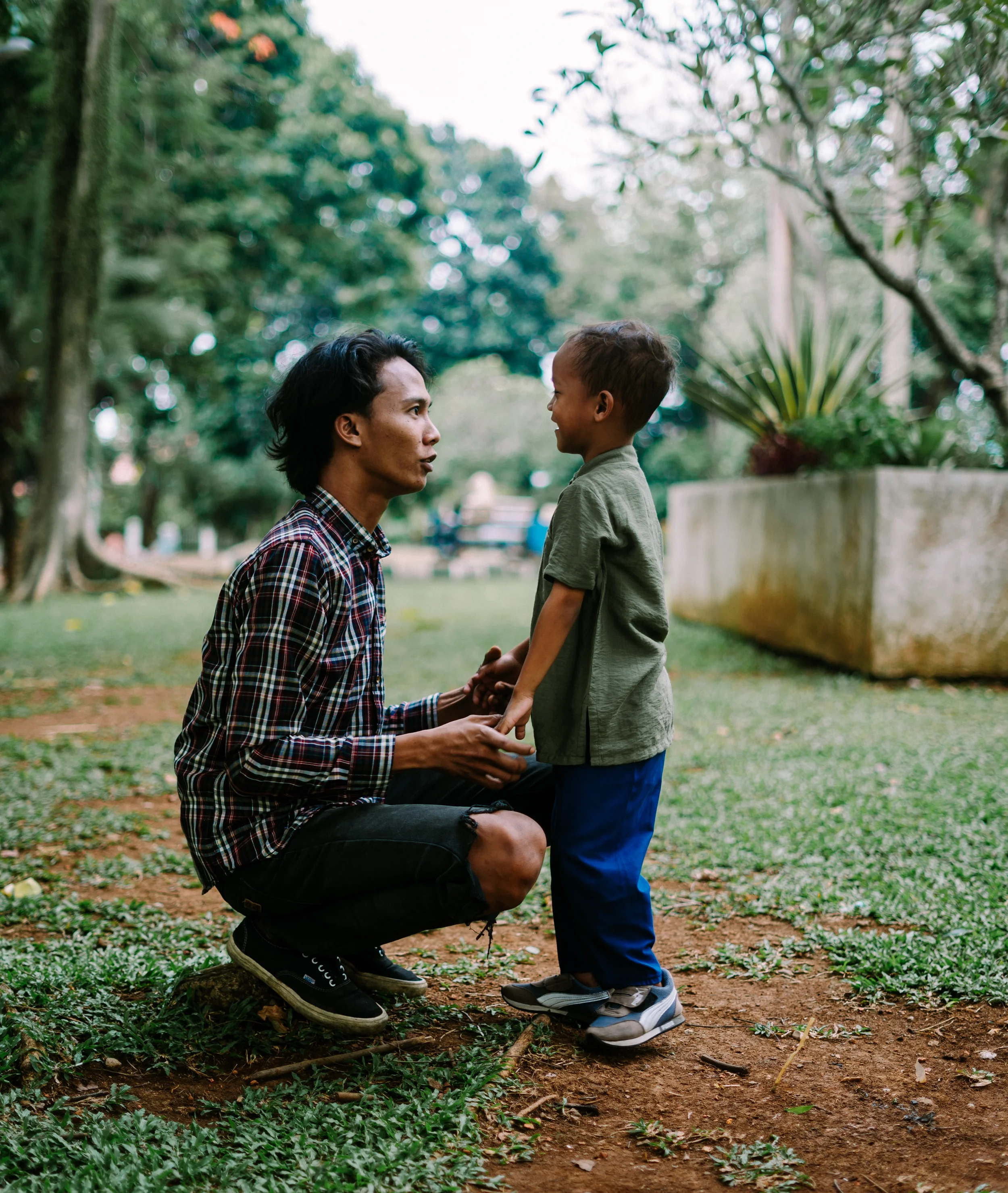 Father kneeling and talking calmly with young child outdoors about climate anxiety