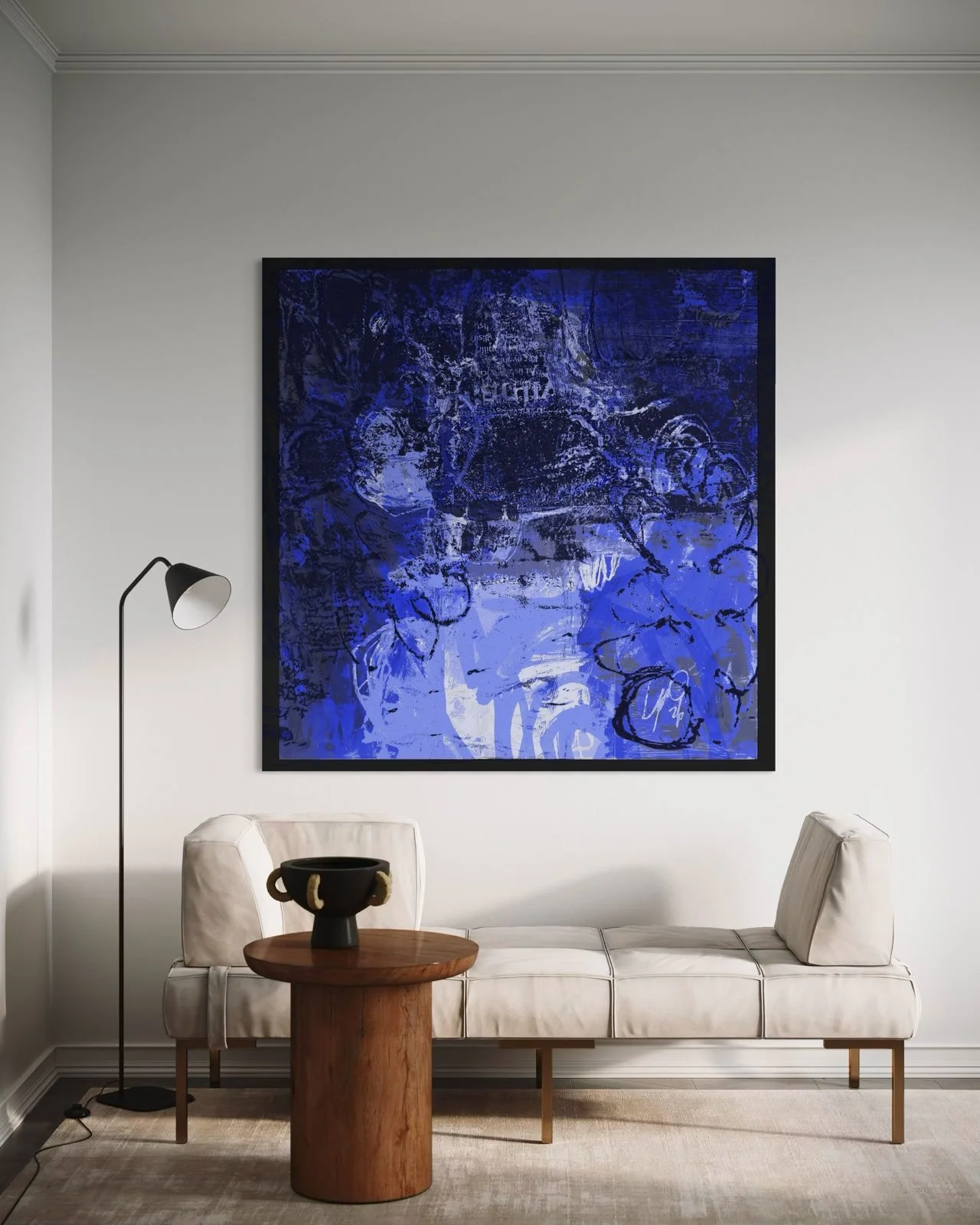 Modern living room with a white sofa, a round wooden coffee table, a black decorative bowl, a tall black floor lamp, and a large abstract blue and black painting on the wall.