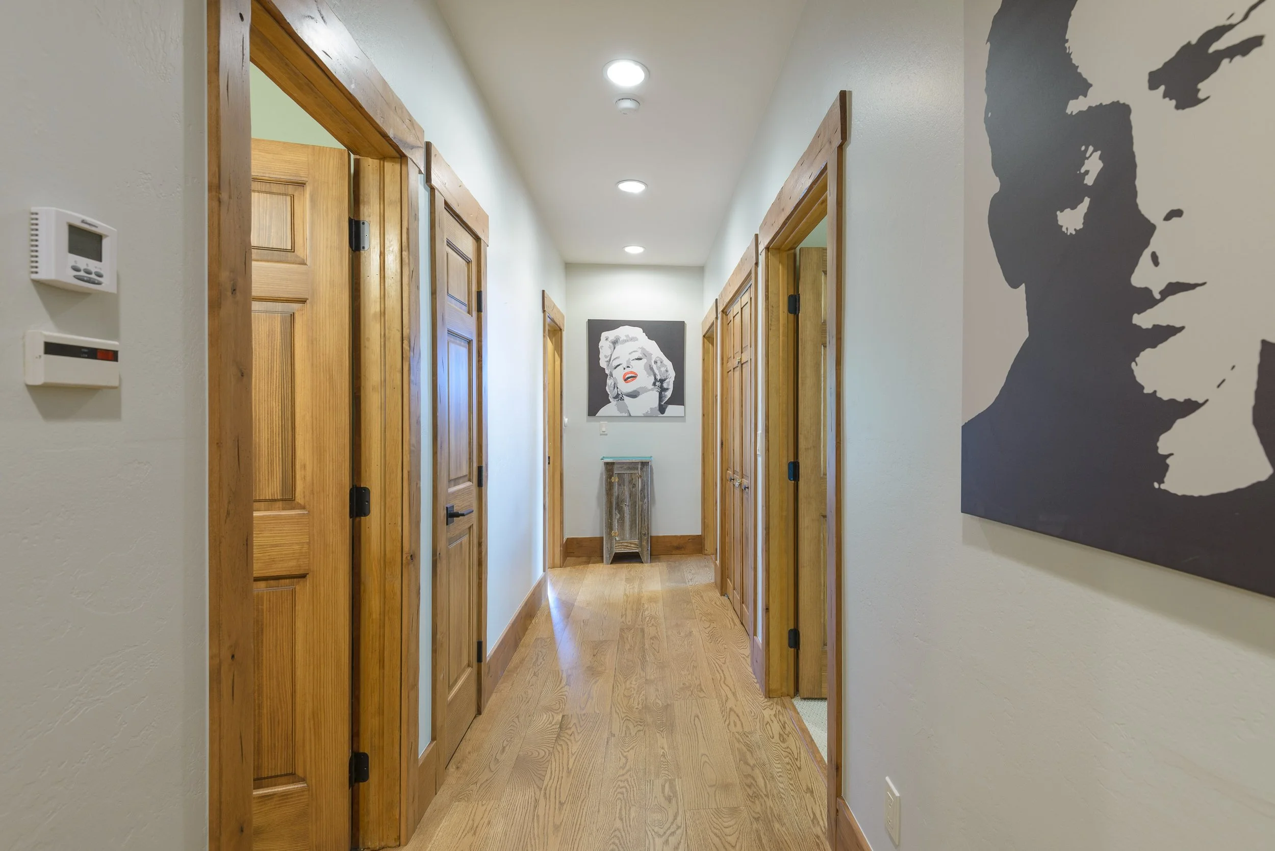 Hallway with wooden doors, white walls, wood trim, and artwork of Marilyn Monroe on the far wall.
